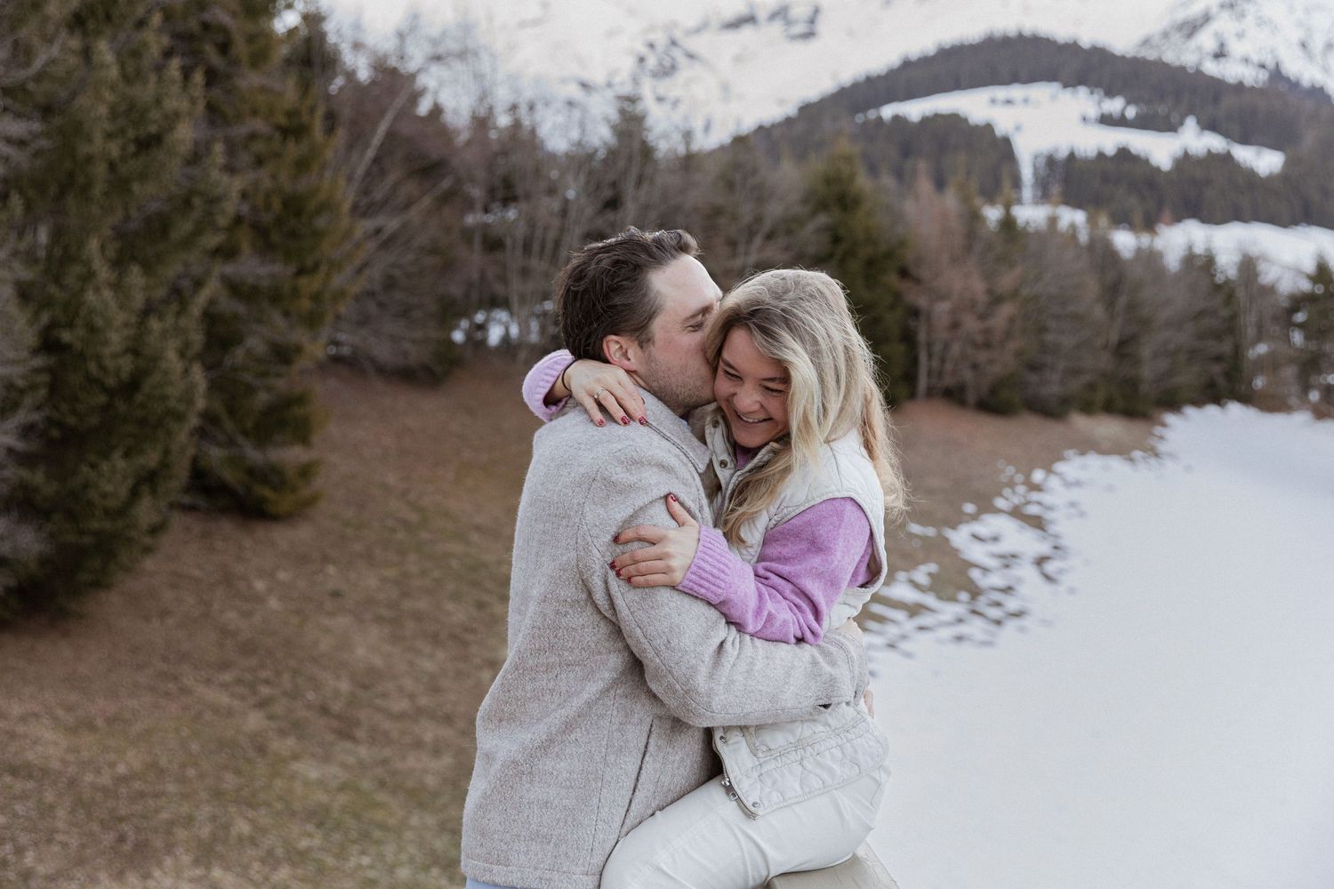 A tender embrace captured against a scenic winter mountain backdrop.