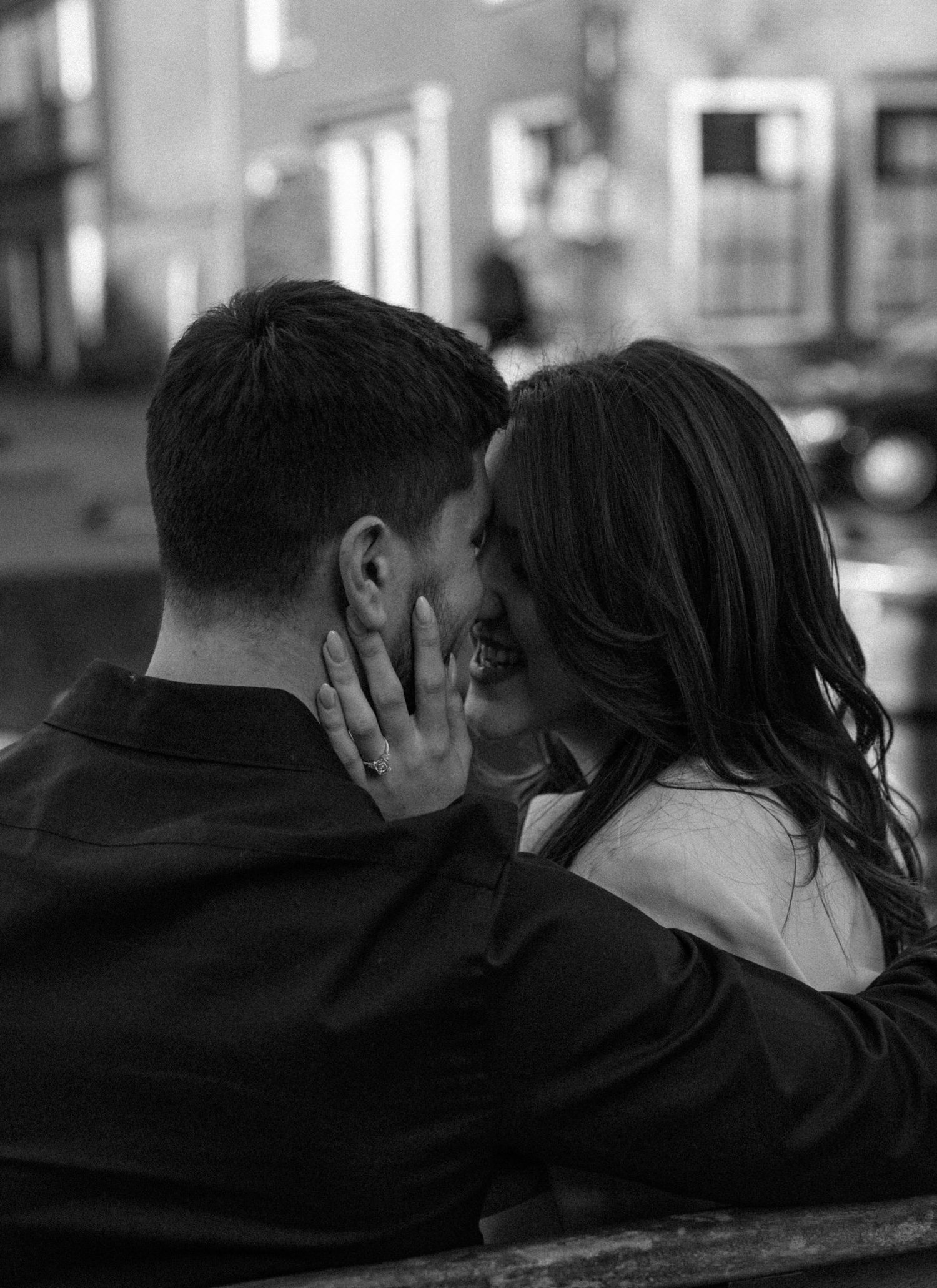 Black and white photo of a smiling couple sharing a romantic moment, the woman tenderly holding the man's face.