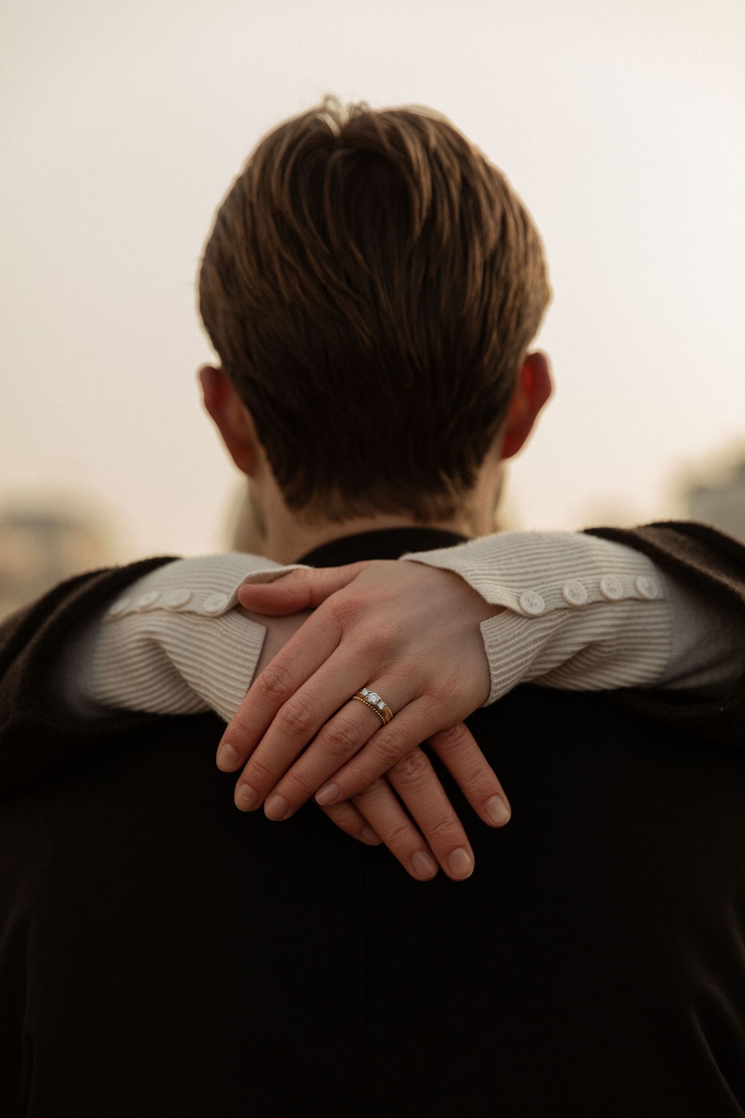 A hand rests gently on a shoulder wearing a dark suit jacket in an intimate black and white photograph.