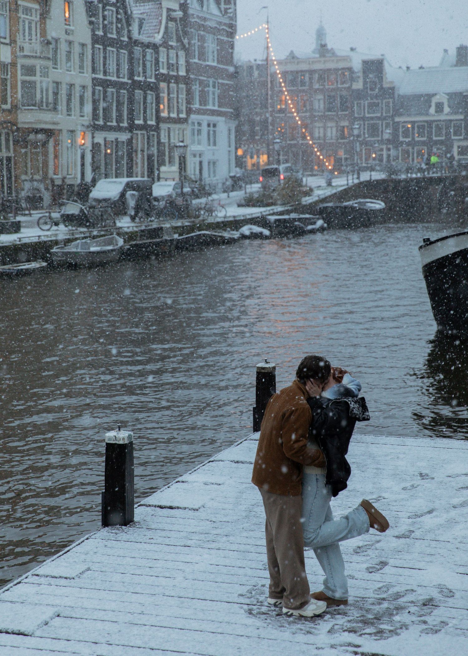 Photographer capturing snowy scenes along Amsterdam canals during winter.