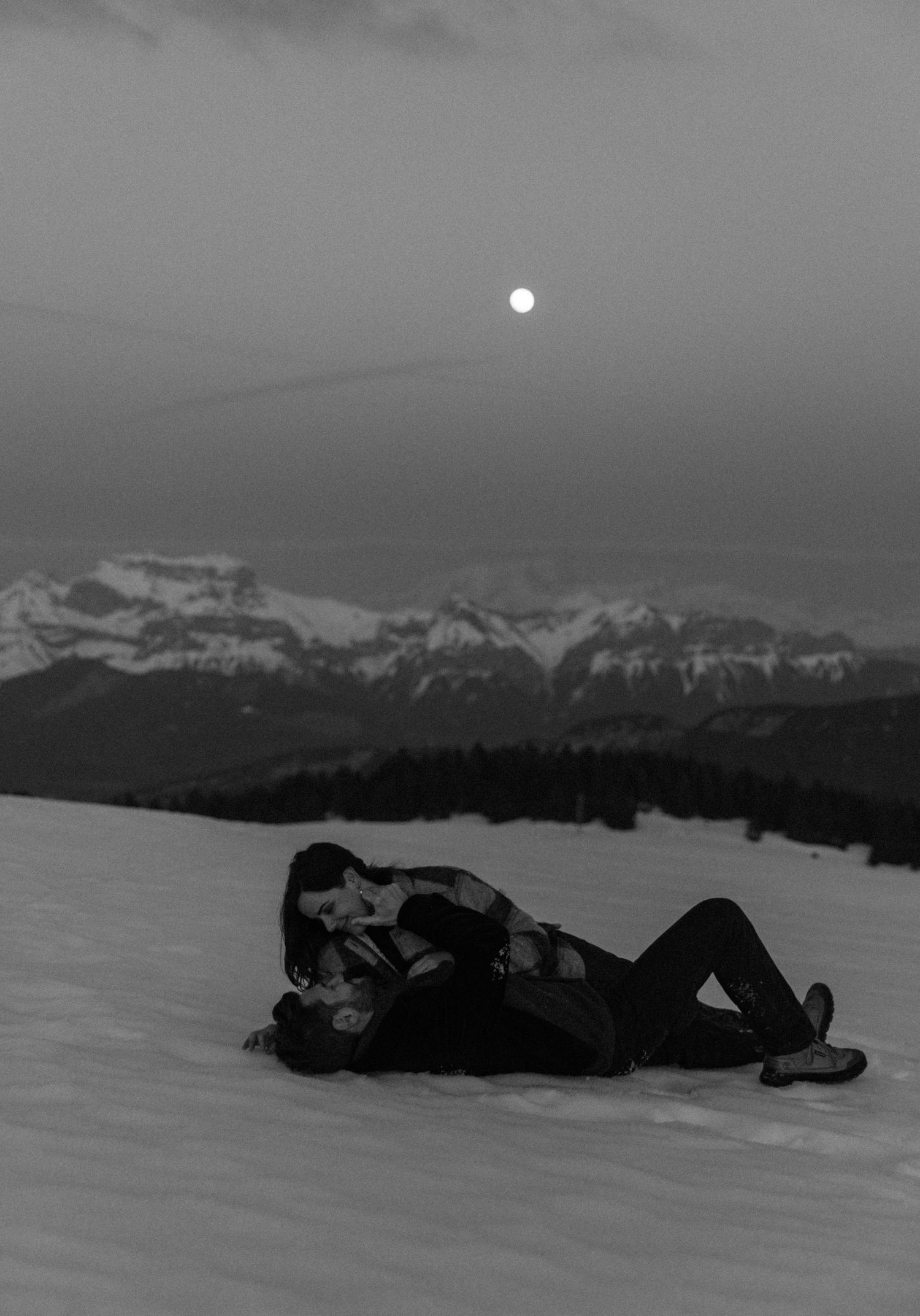 A sequence of black and white photos showing silhouettes resting in snowy mountains with a full moon in the background.