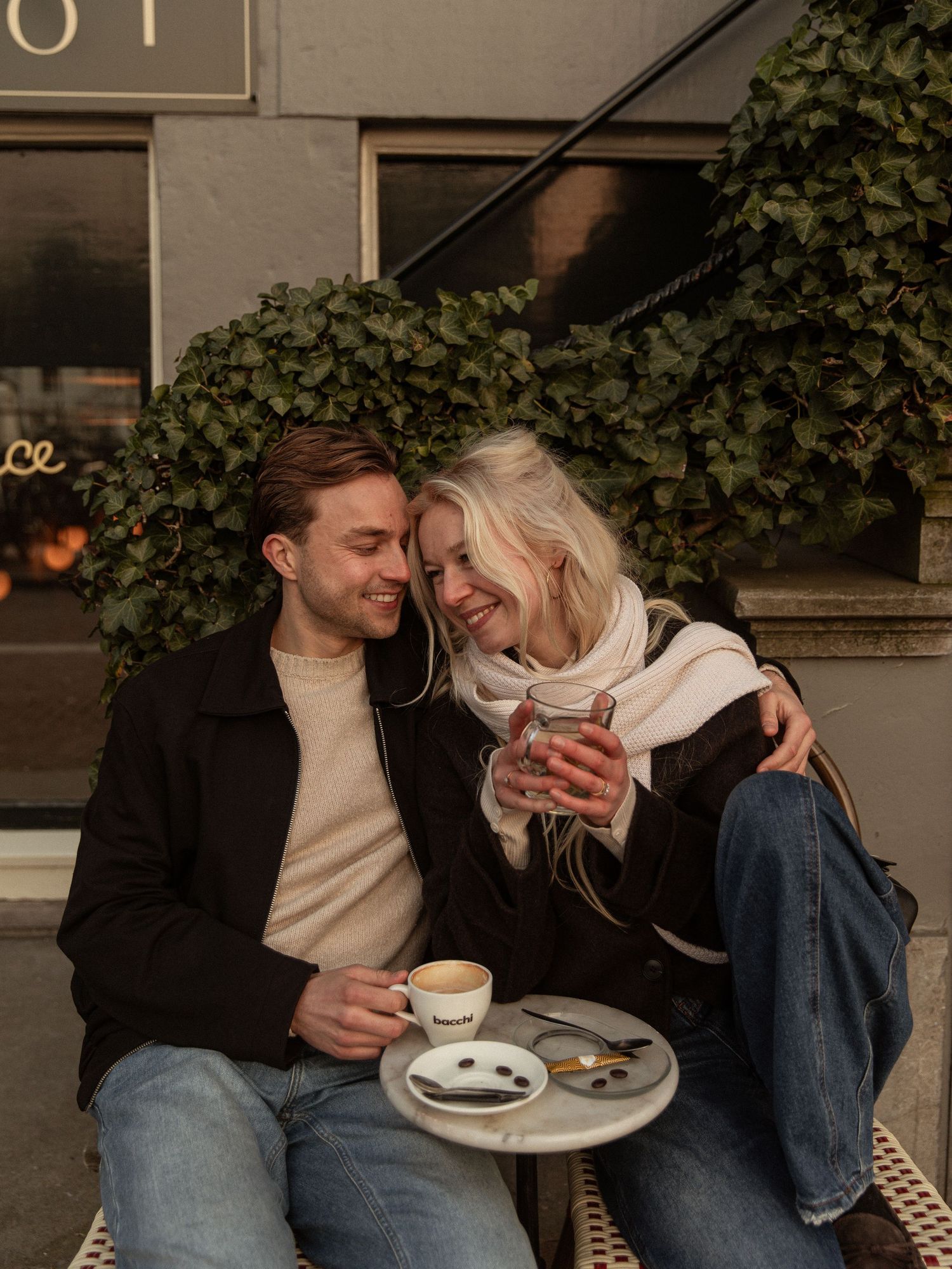 A couple shares intimate moments while enjoying coffee and dessert at an outdoor cafe table.