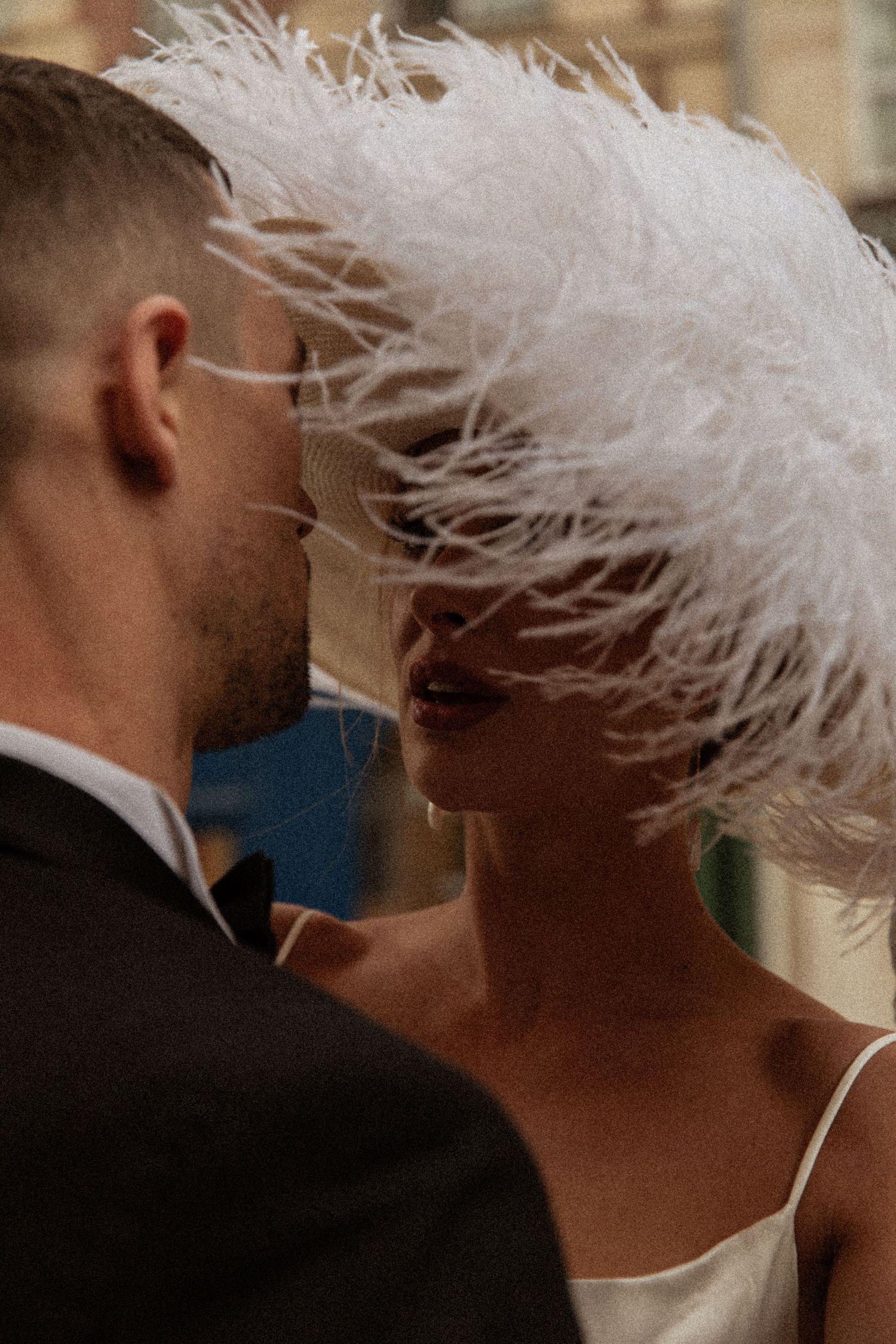 A romantic moment between a couple with a white feathered headpiece creating an elegant silhouette.