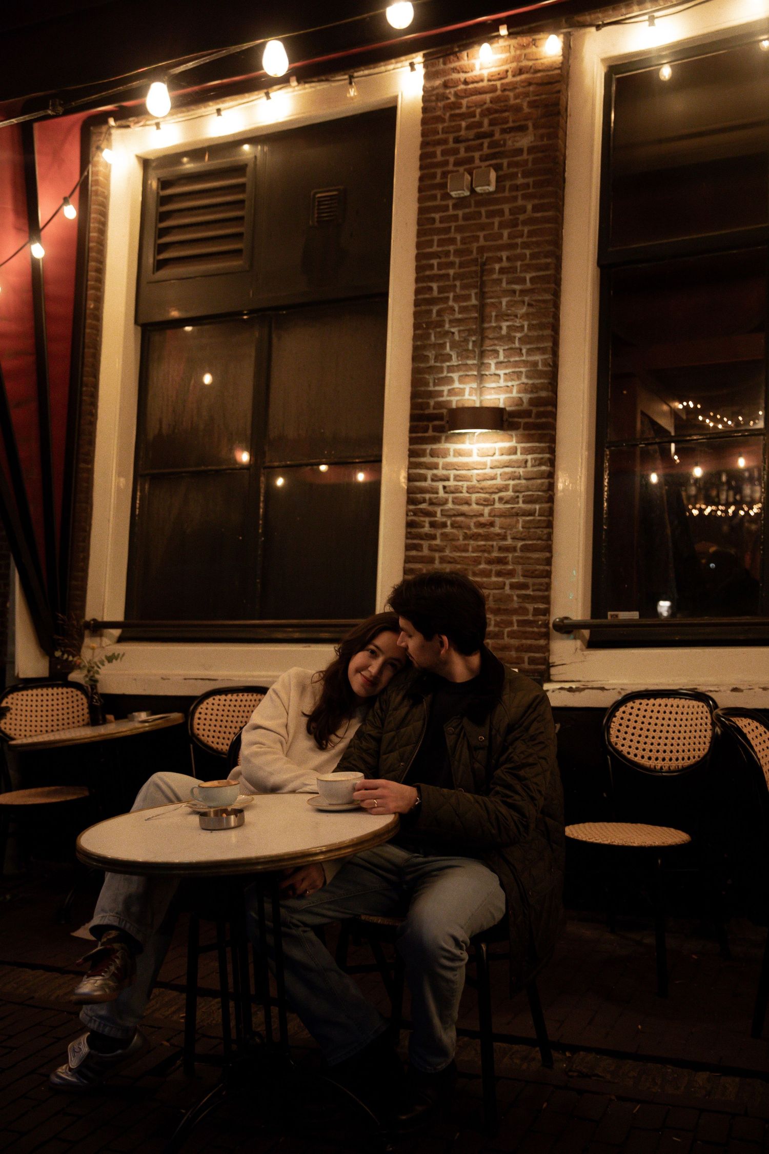 Couple sharing a romantic moment in a dimly lit restaurant with exposed brick walls.