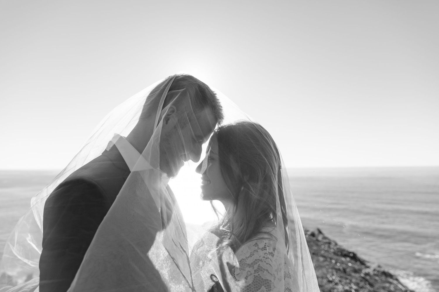 Black and white photo series showing a couple embracing on a beach during a romantic photoshoot.