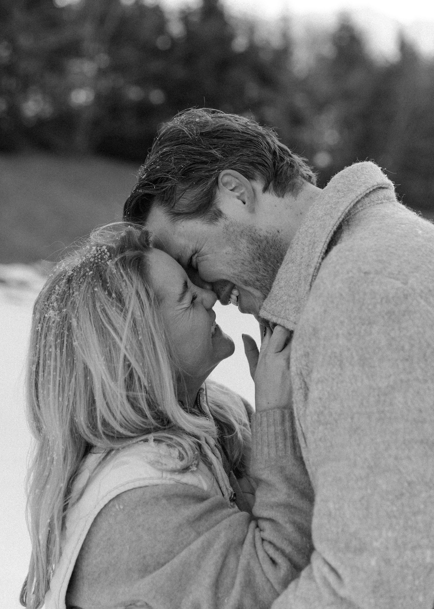 A couple in winter clothing sharing an intimate moment in the snow.
