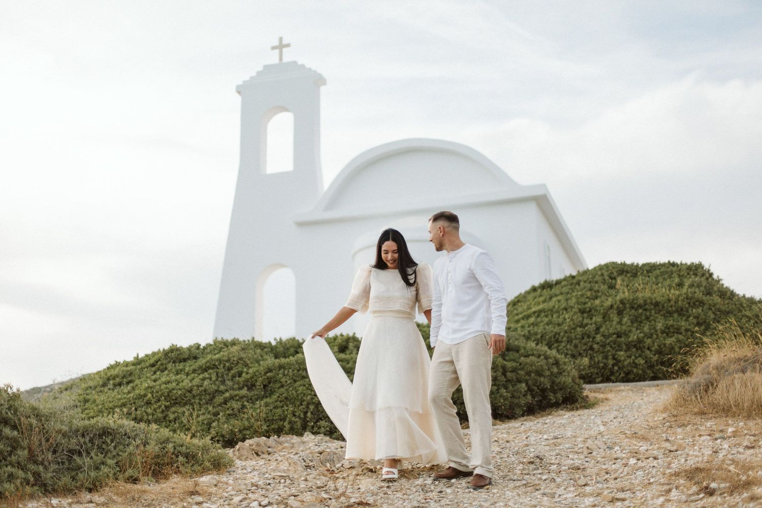 Couple walking together in front of a white church in Samos, Greece