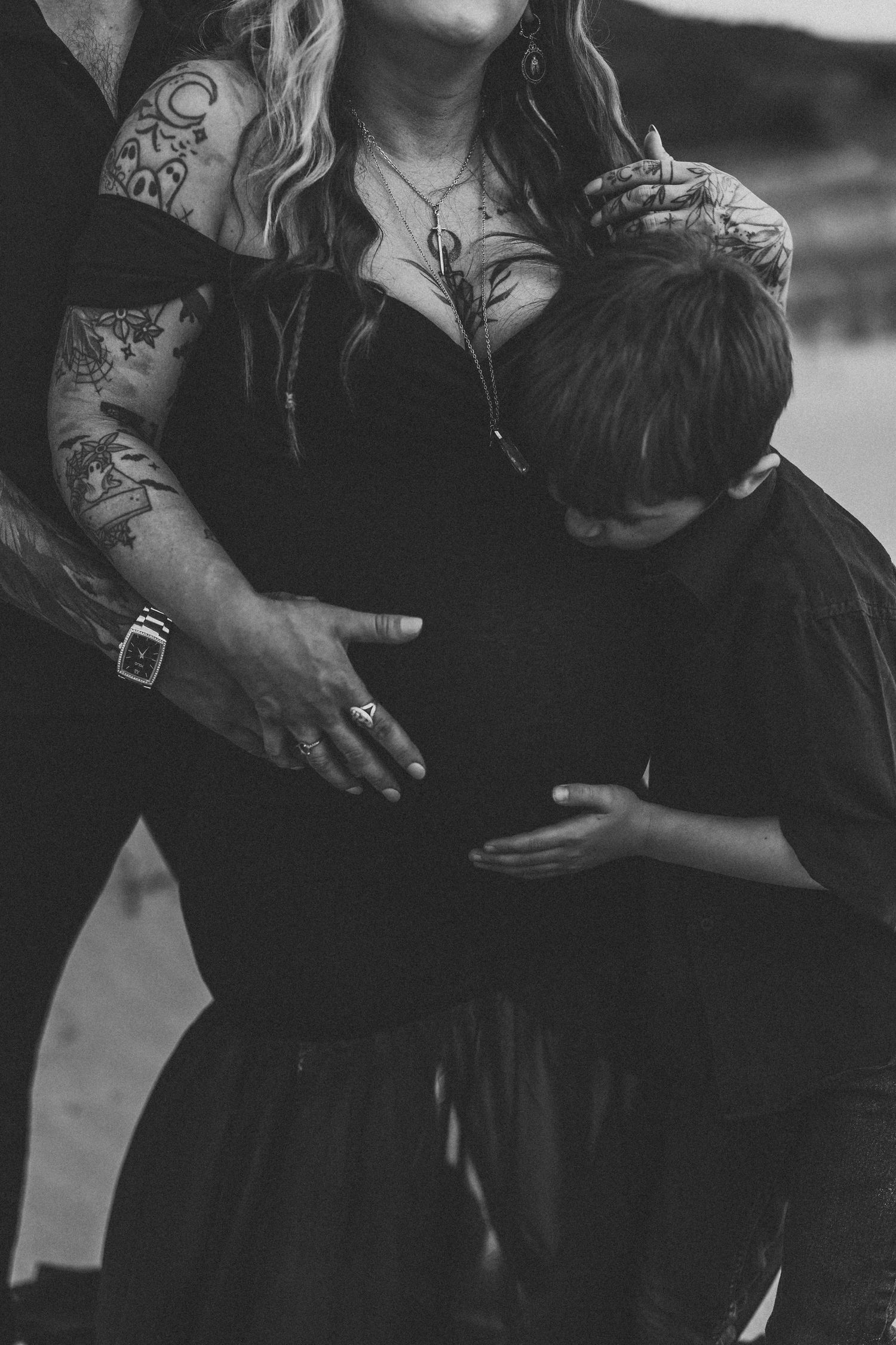 Intimate maternity portrait showing couple embracing in dark clothing.