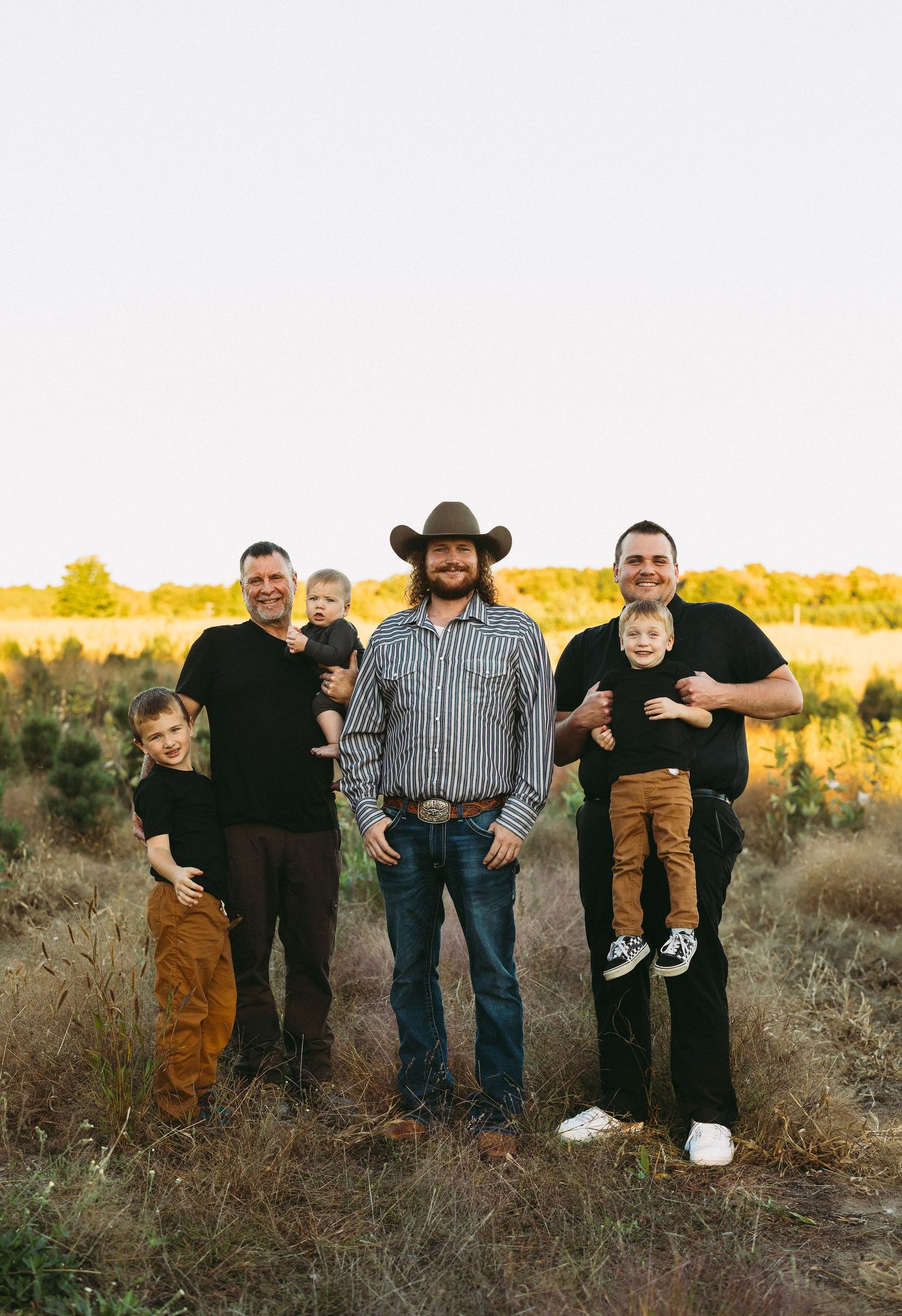 Group of family members standing together in field during sunset.
