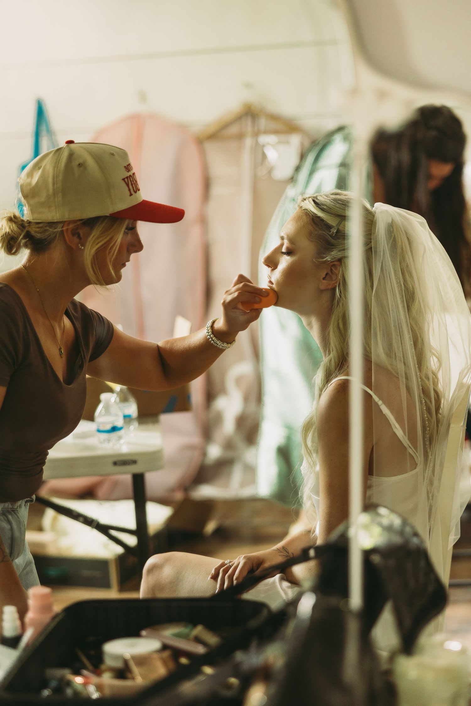 Behind-the-scenes moment of wedding day makeup preparation in a dressing room.