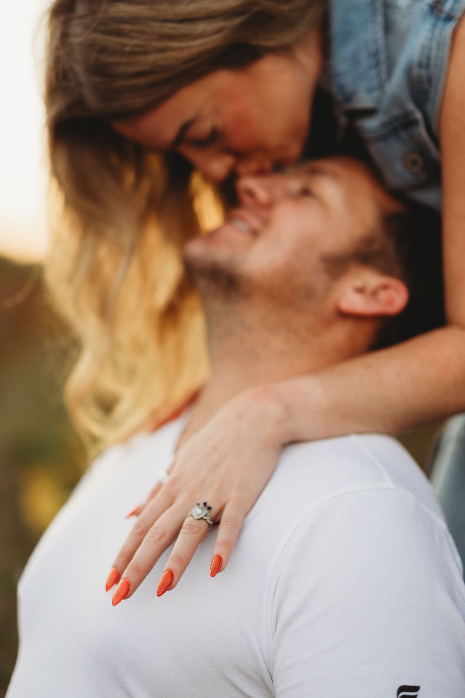 Close-up romantic engagement photos showing couple embracing with diamond ring prominently displayed.