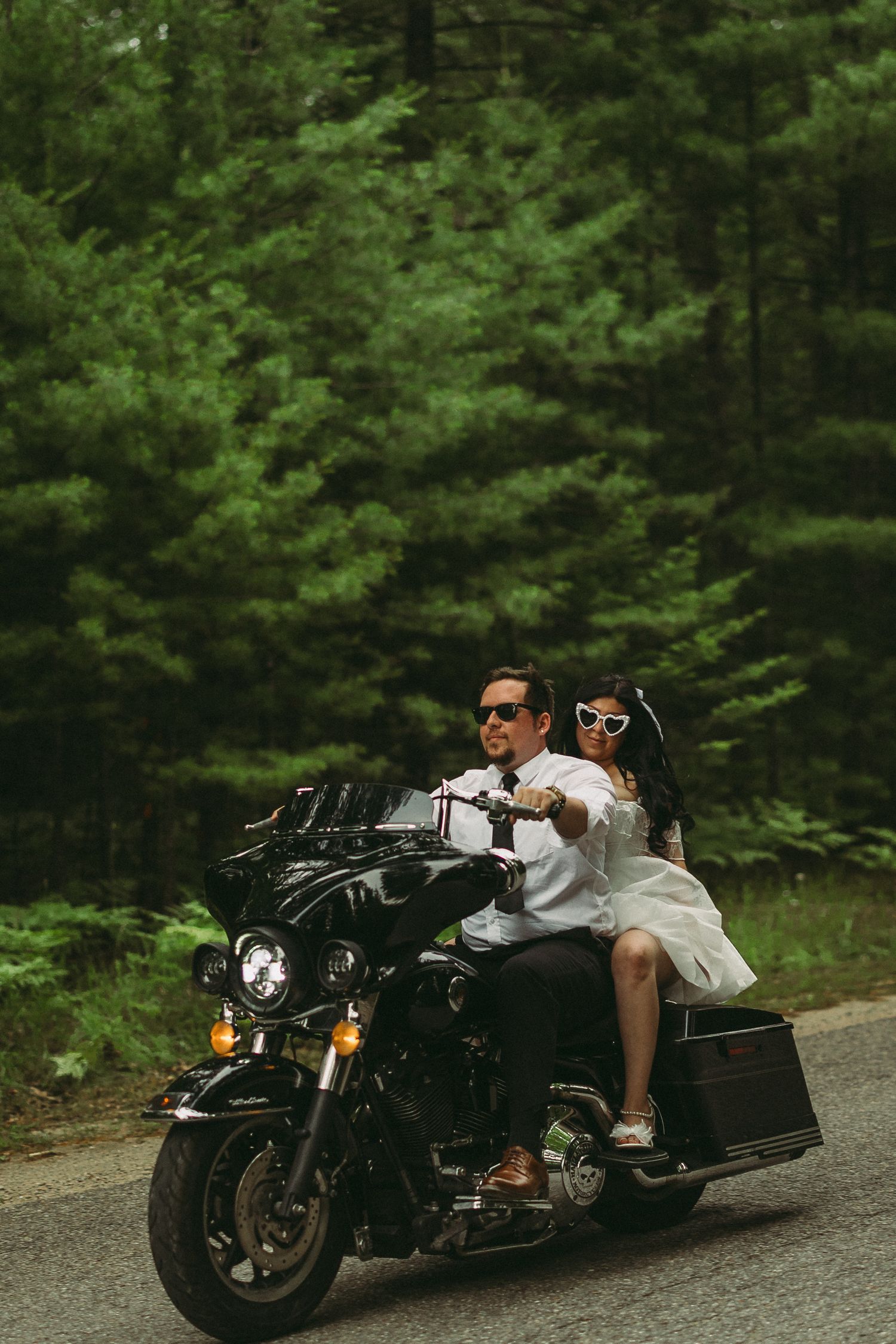 Stylish motorcycle photo session in a lush green forest setting.