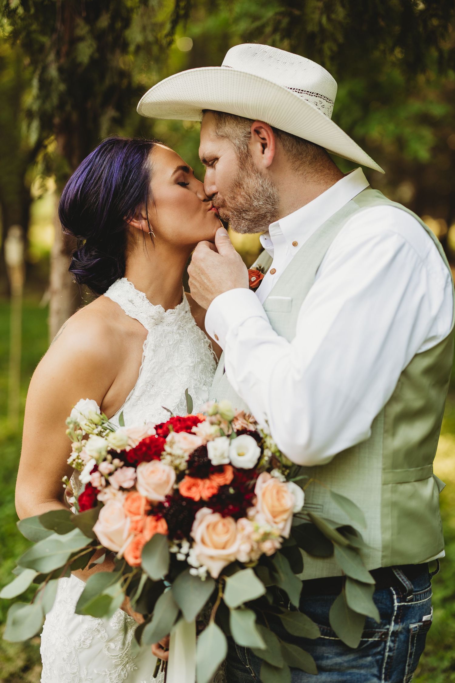 Romantic wedding couple embracing outdoors with a beautiful floral bouquet.