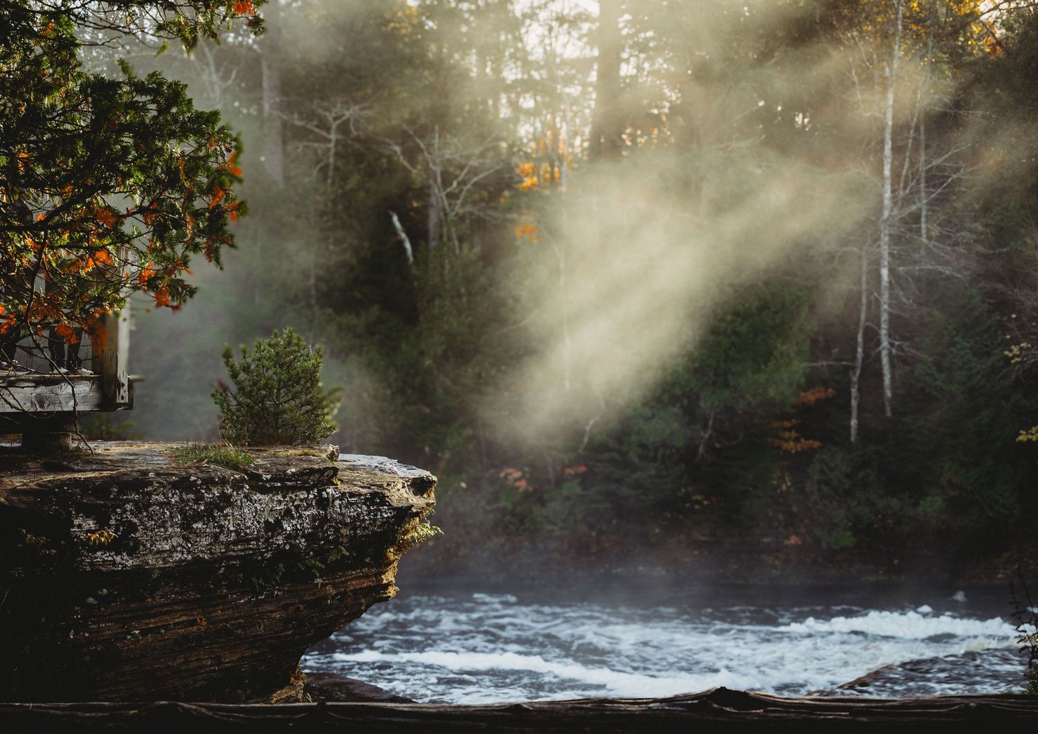 Misty waterfall cascading through autumn forest landscape.