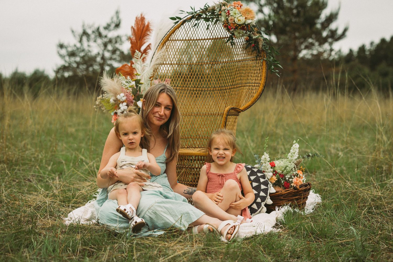 A series of outdoor family portraits in a rustic field setting with wicker chairs and natural decor.
