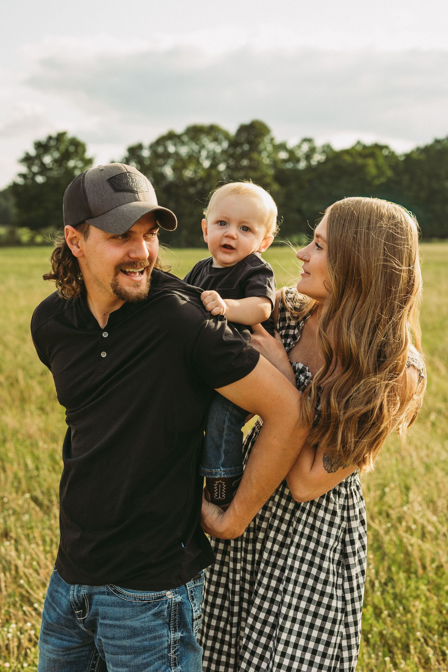 Family sharing playful moments and laughter in a sunlit summer field.