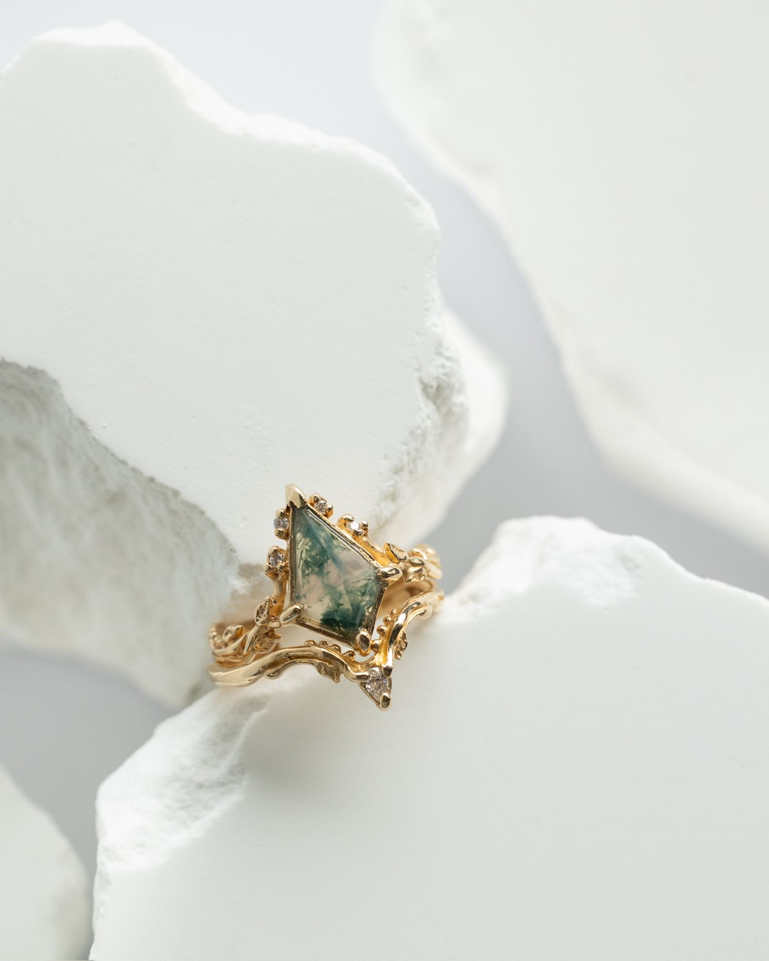 Gold ring with green gemstone photographed among white crystalline formations.