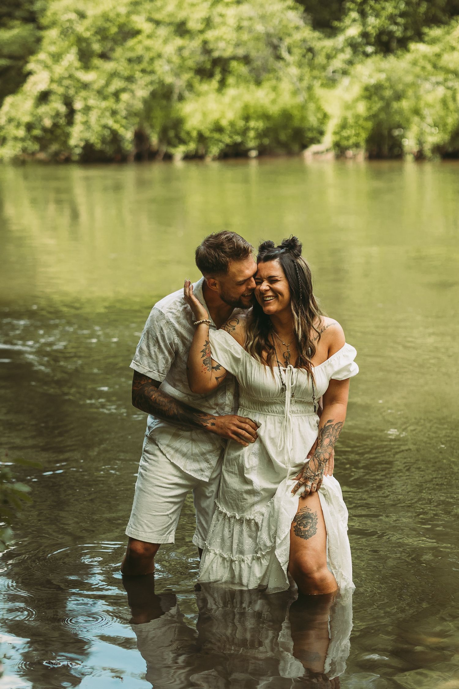 Couple in white outfits sharing romantic moments while standing in a river.