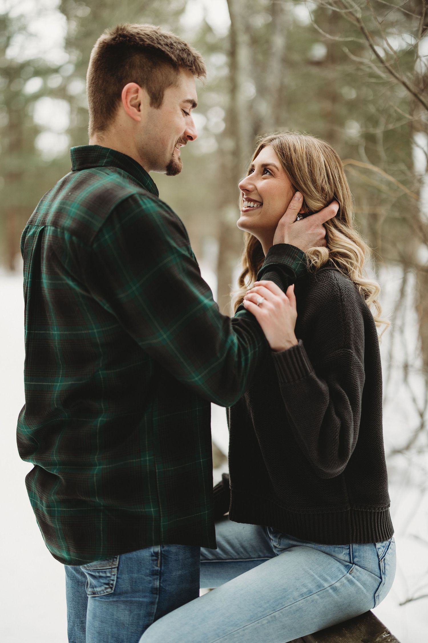 Candid winter engagement photos showing couple laughing and embracing in snow.