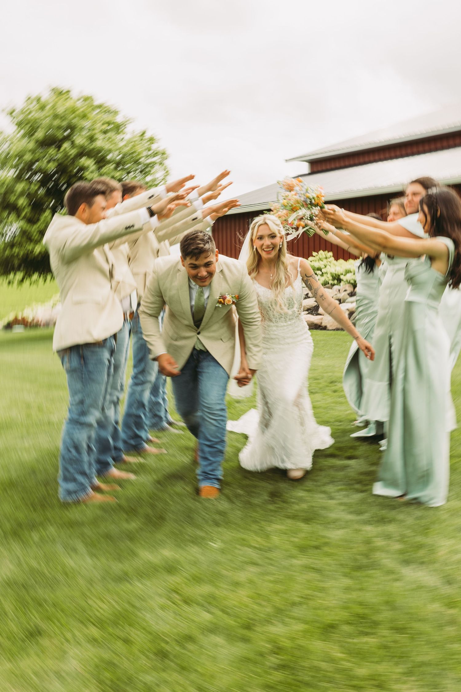 Wedding party poses playfully on grass in coordinated mint and denim outfits.