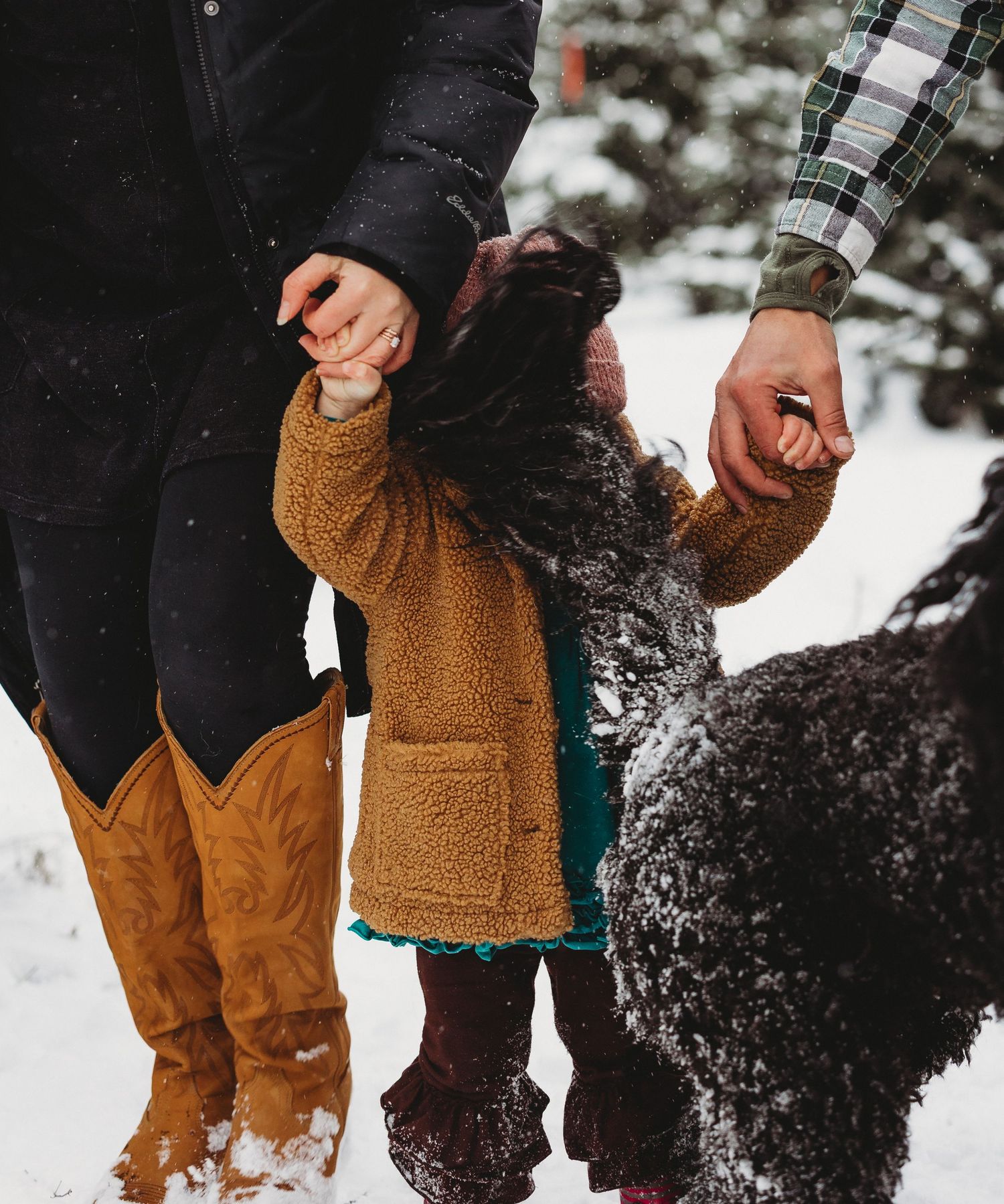 Close-up of winter boots and cozy clothing in the snow among evergreen trees.