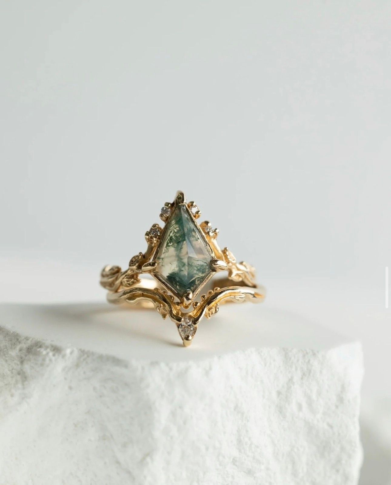 Delicate gold ring with aquamarine gemstone displayed on white crystal surface.