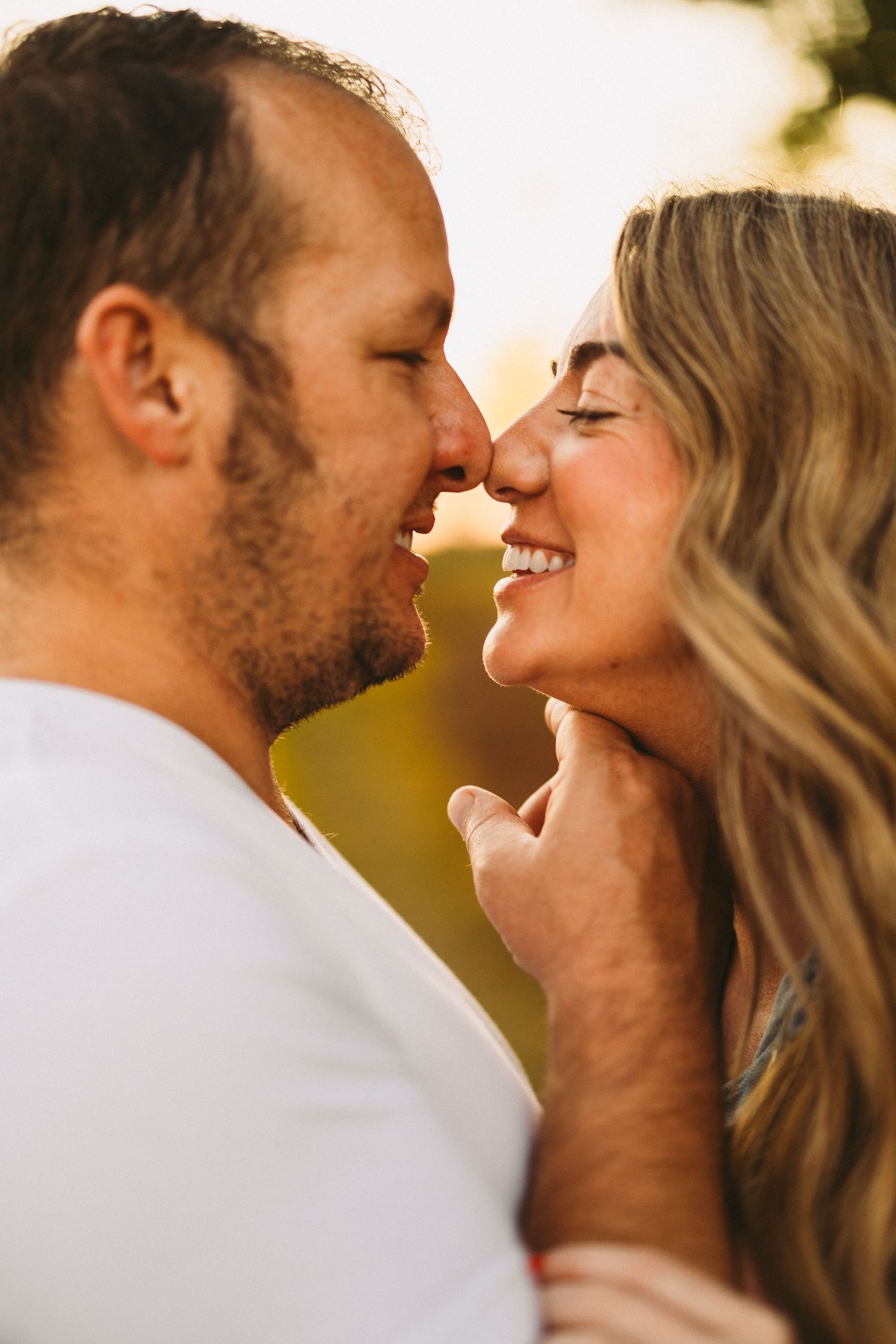 A romantic couple shares an intimate moment at sunset with soft golden lighting.