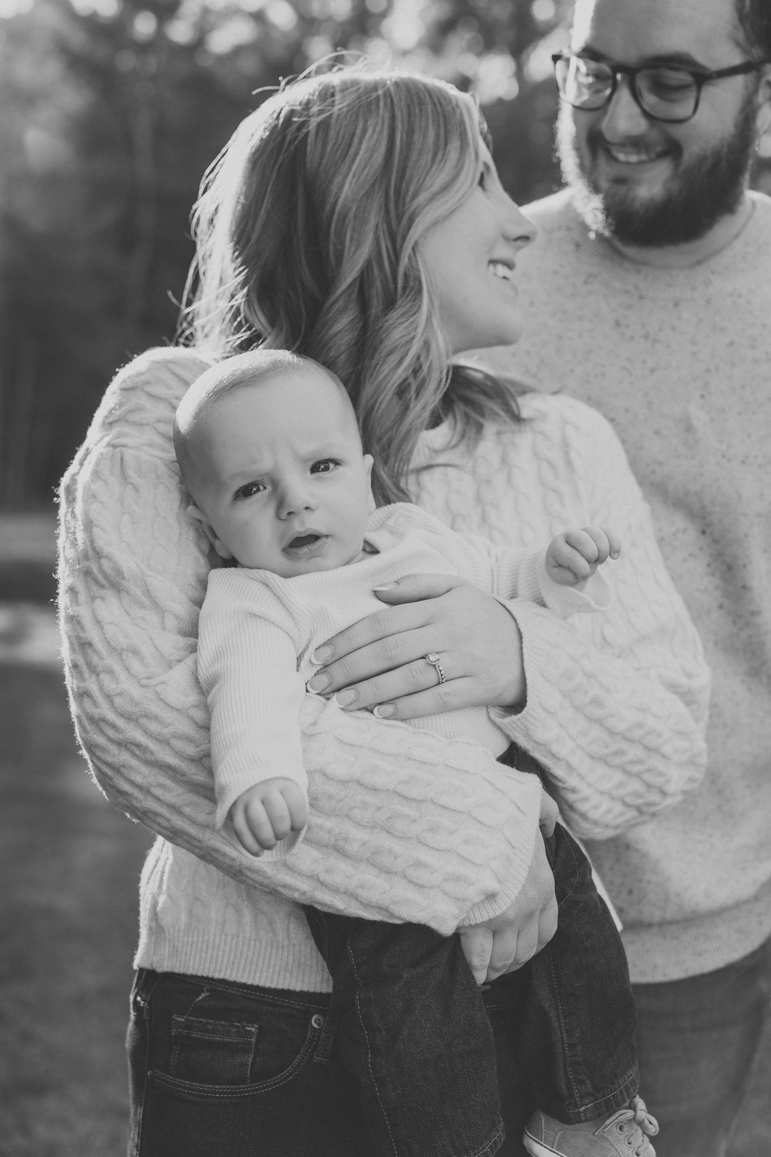Black and white series showing intimate family moments outdoors wearing matching cable knit sweaters.