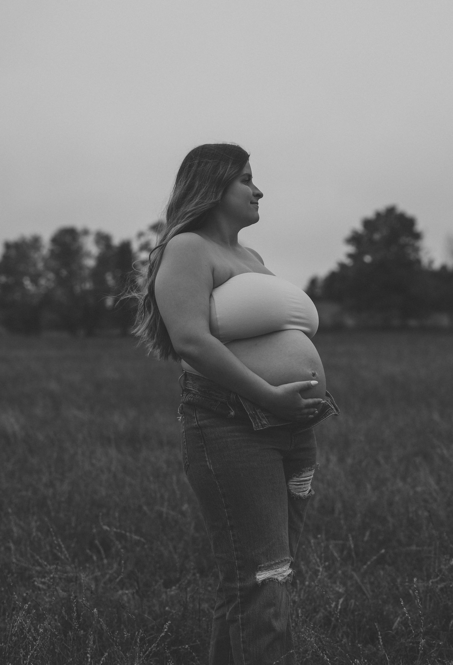 Artistic black and white maternity silhouette in an open field.