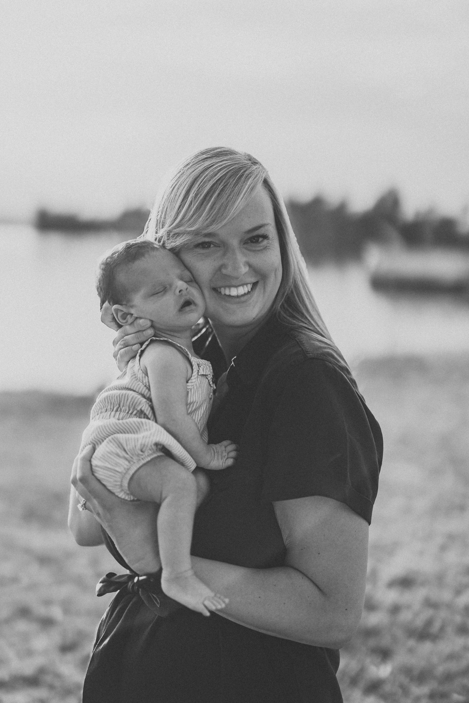 A joyful black and white series of photos showing a parent and baby embracing outdoors in a field.