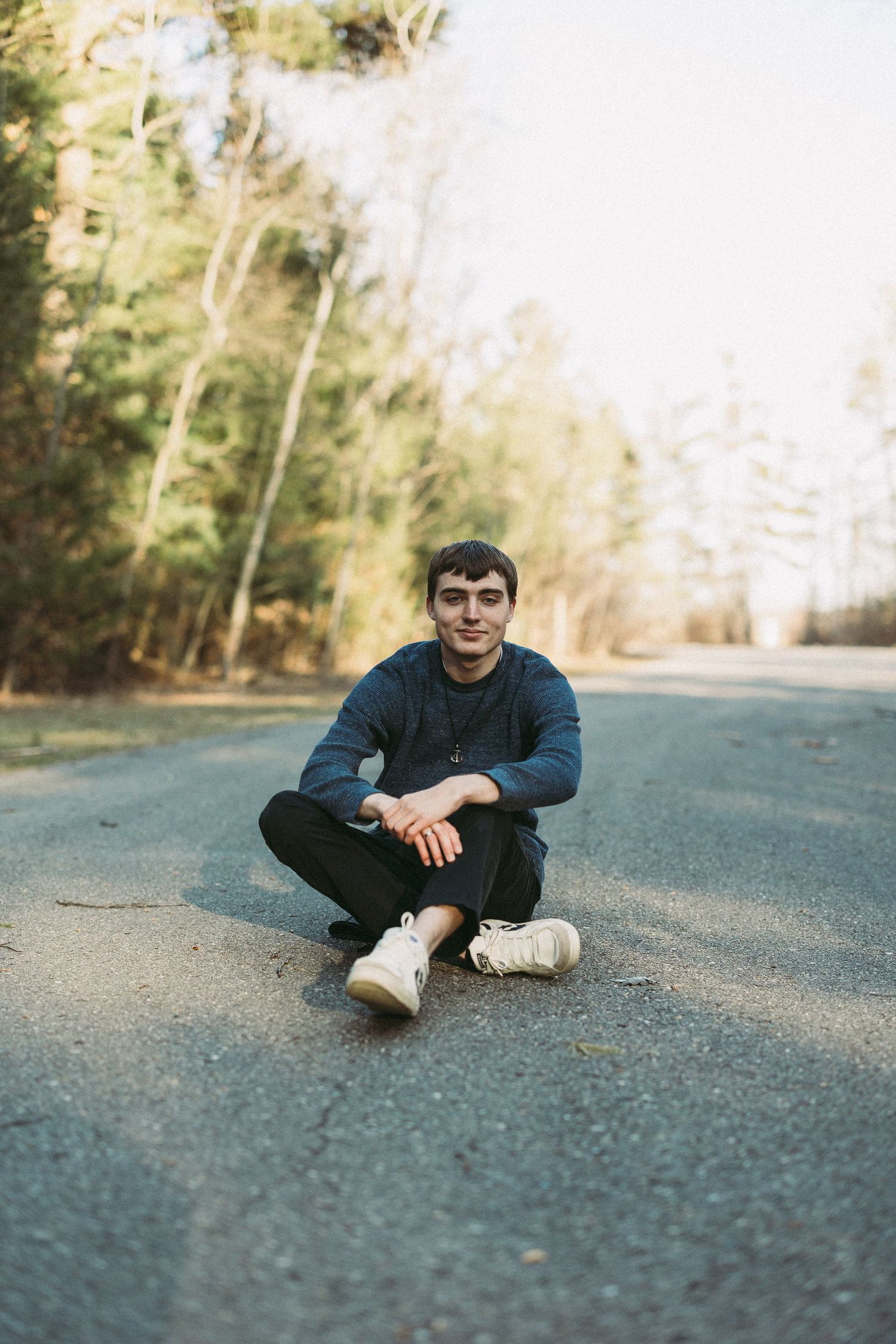Casual outdoor portrait session on asphalt road with trees in background.
