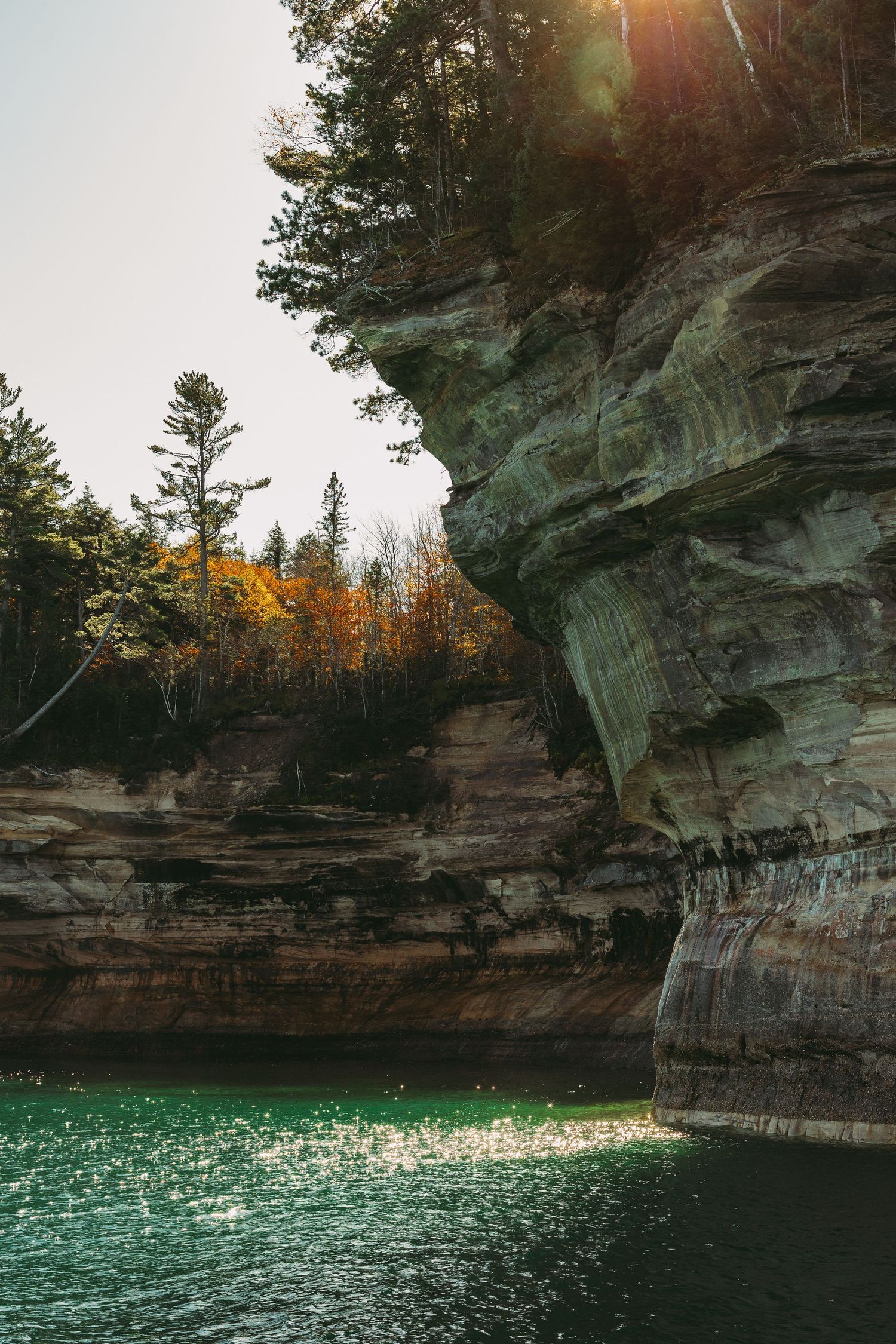Dramatic limestone cliffs overlooking turquoise water at sunset.