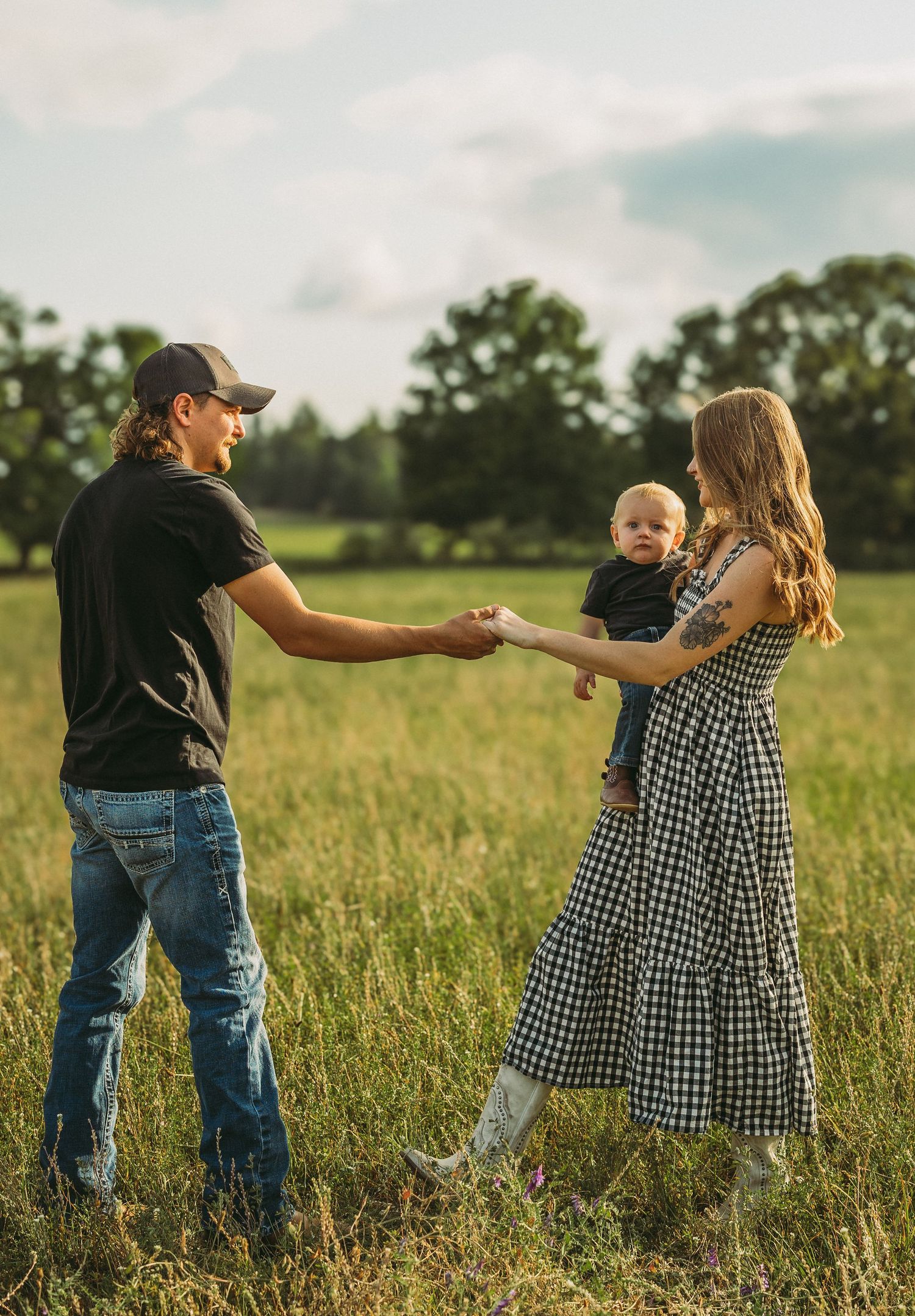 Family dancing and playing together in a tall grass meadow during golden hour.