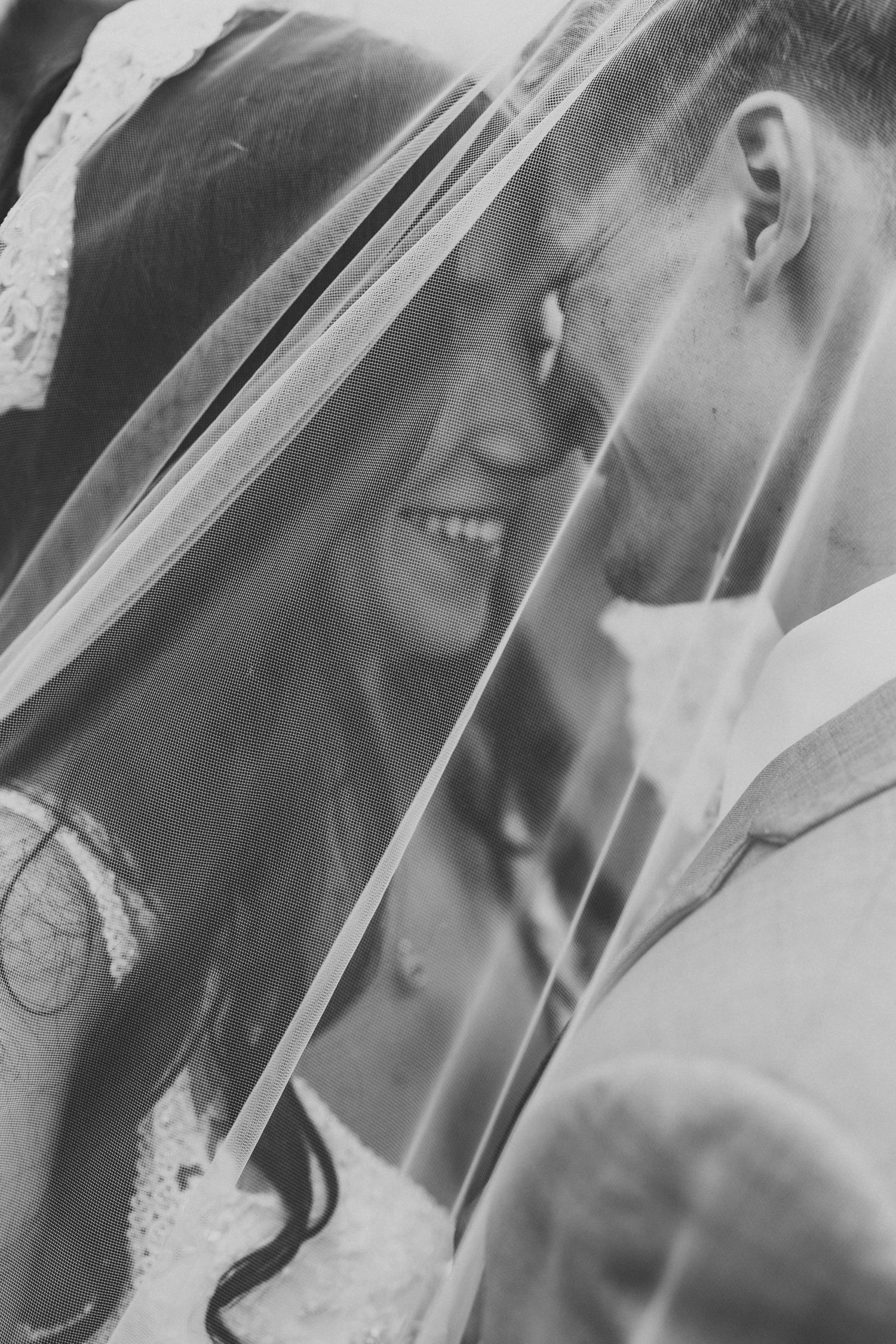 Intimate black and white wedding portrait captured through a delicate veil.