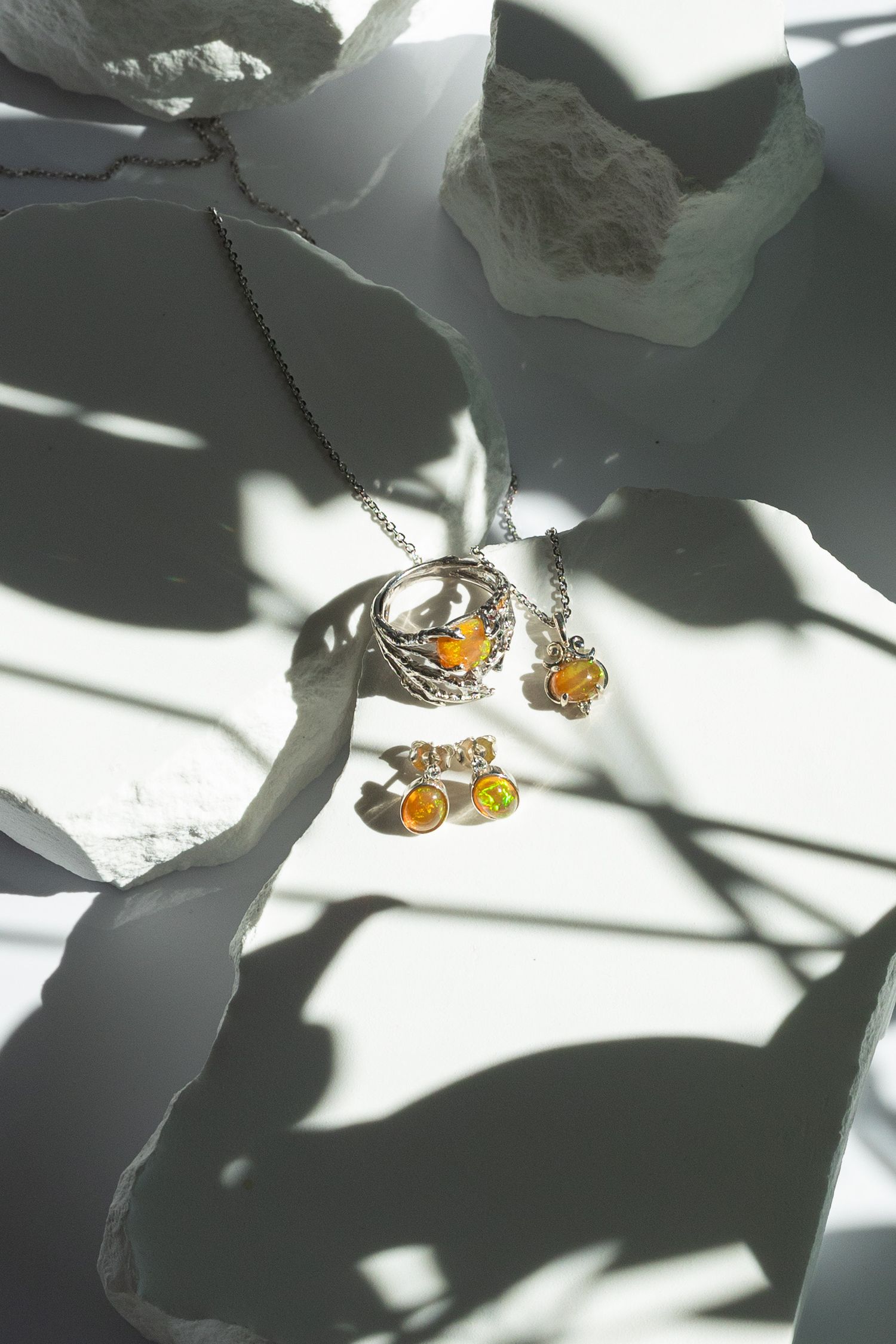 Amber and silver jewelry photographed with artistic shadows on white background.