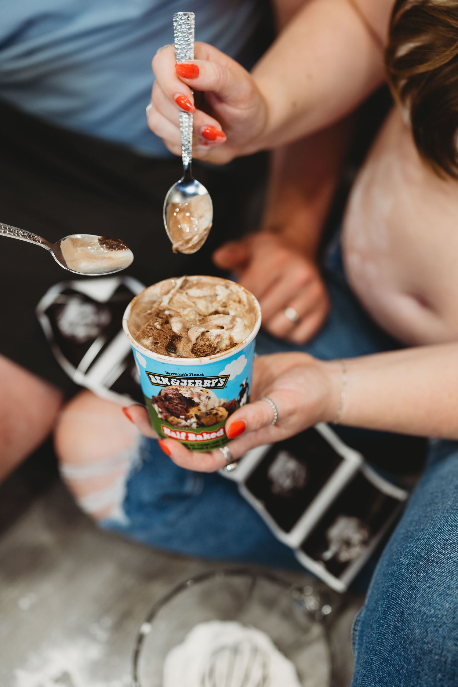 Couple sharing Ben & Jerry's Half Baked ice cream with spoons over ultrasound photos during pregnancy.