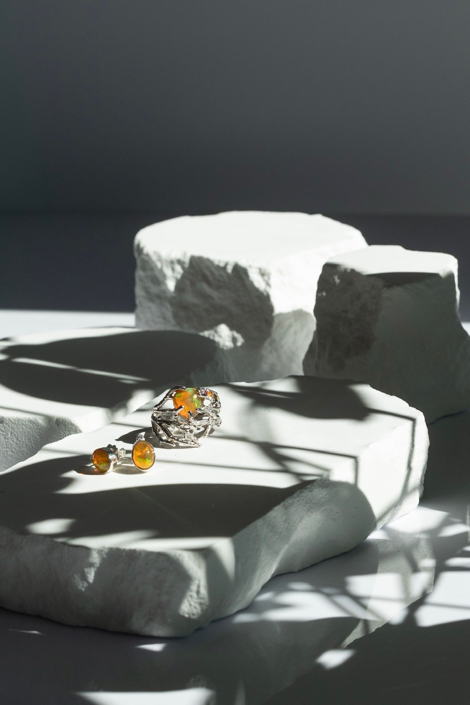 Delicate amber jewelry pieces casting dramatic shadows on white textured paper.