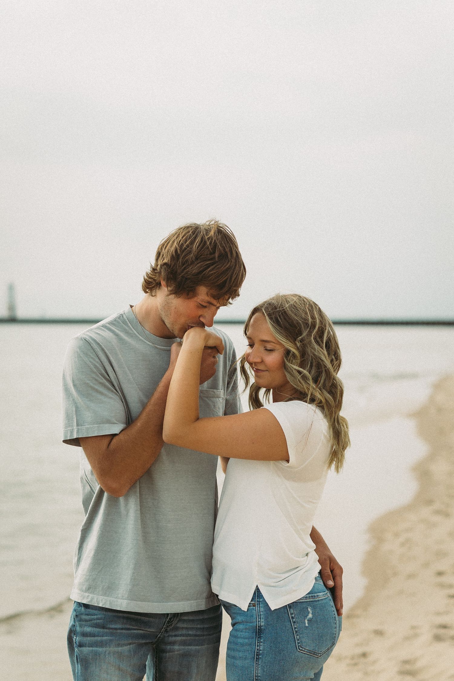 Intimate beachside moment between two people wearing casual denim and t-shirts.