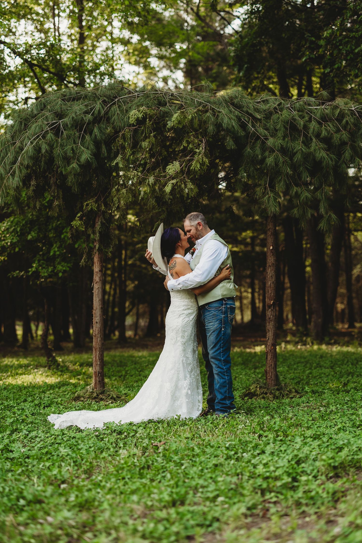 Romantic wedding couple embracing in a lush green forest setting during their photoshoot.