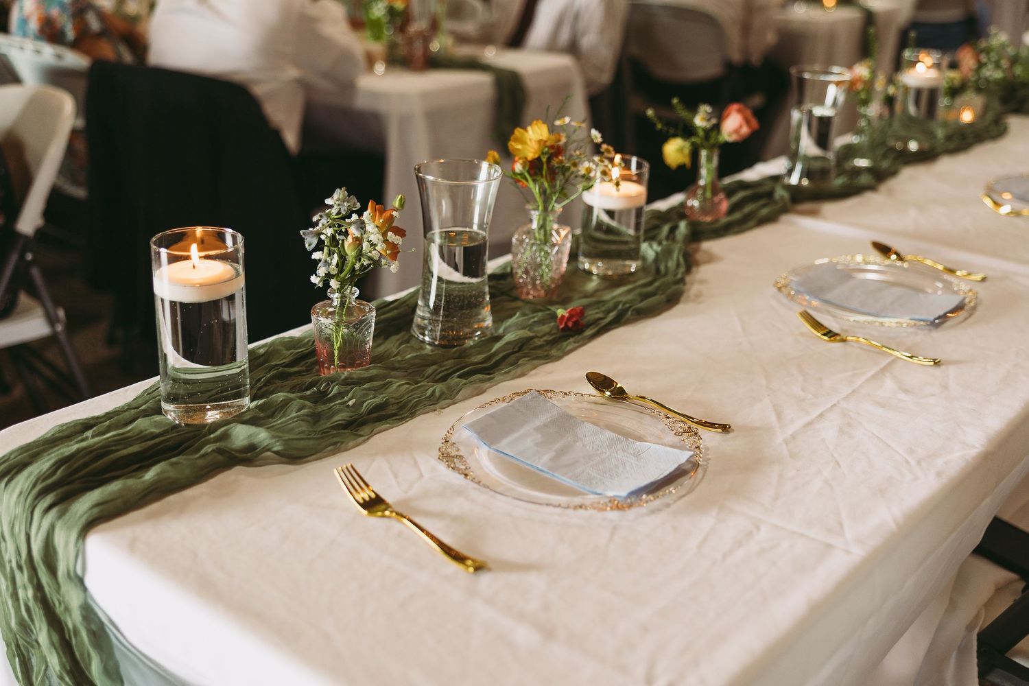 Elegant wedding table setting with white linens, greenery, and candlelight decorations.