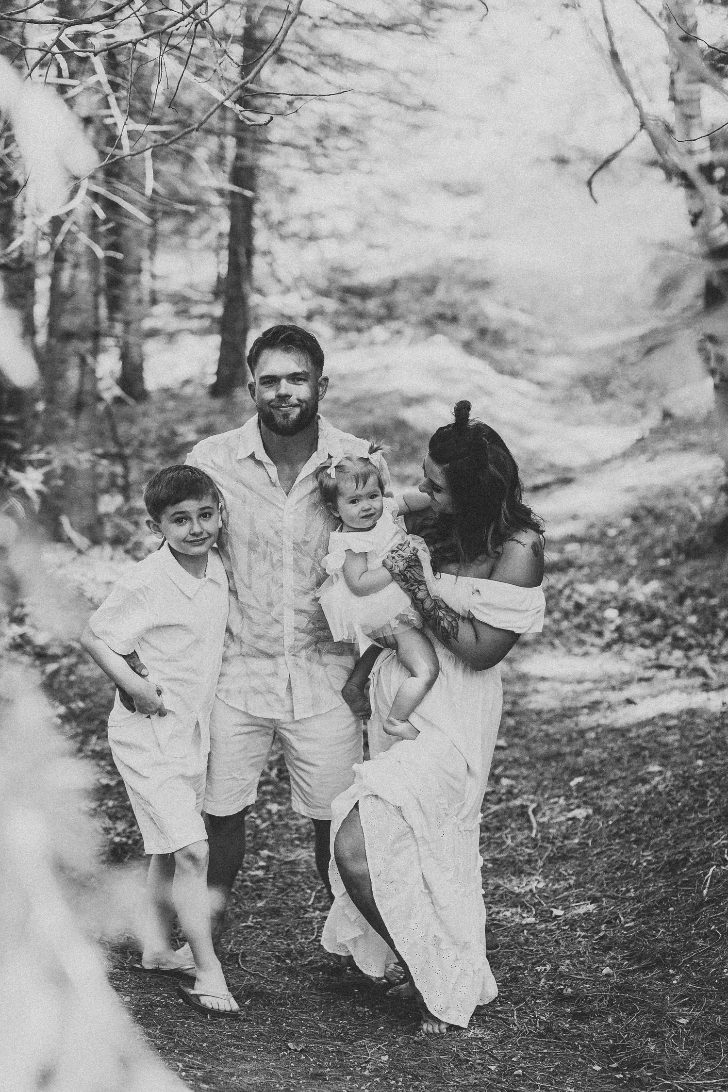 Black and white photos showing playful family moments in a wooded setting.