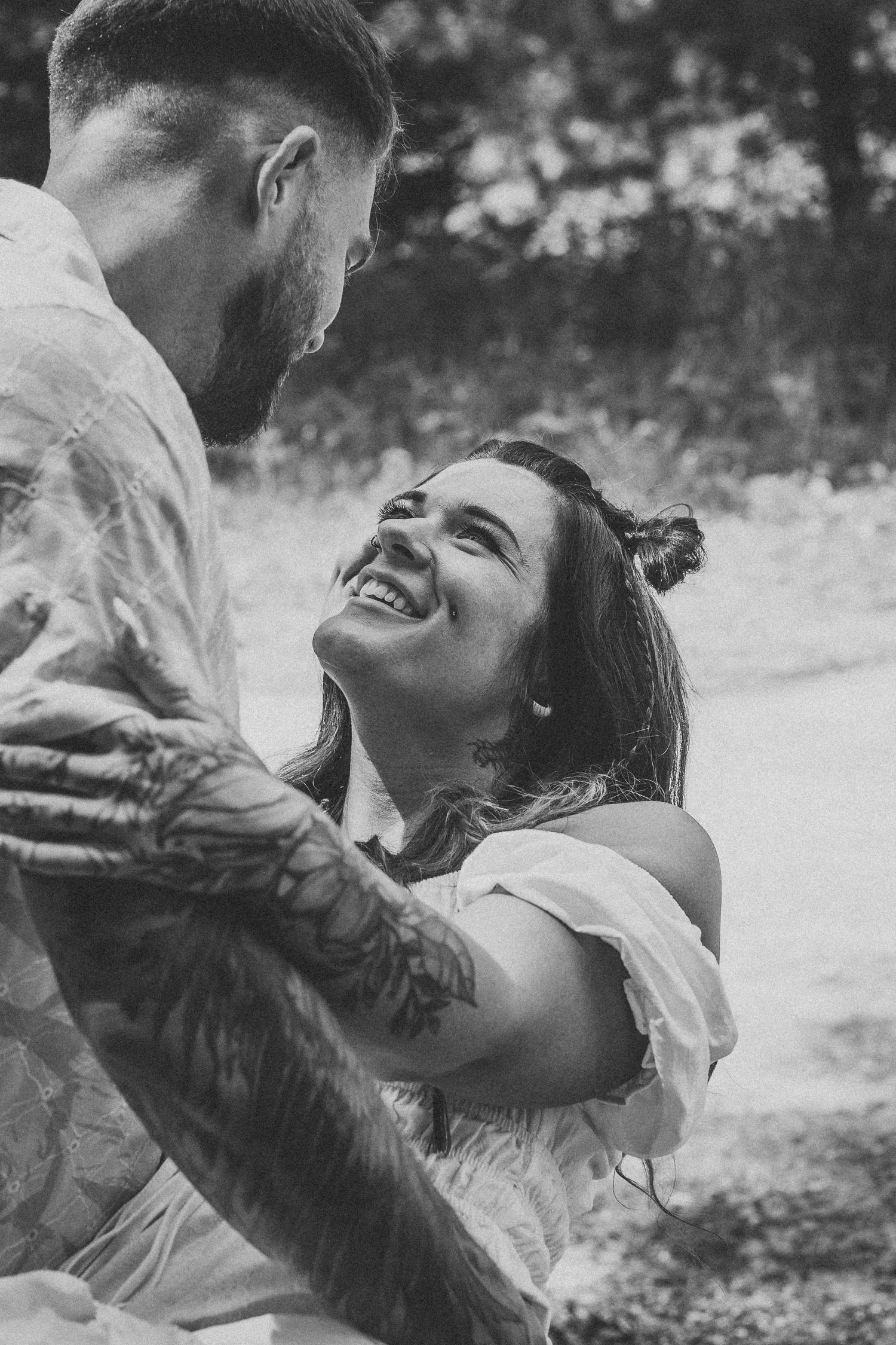 Black and white photo of joyful couple laughing together outdoors.