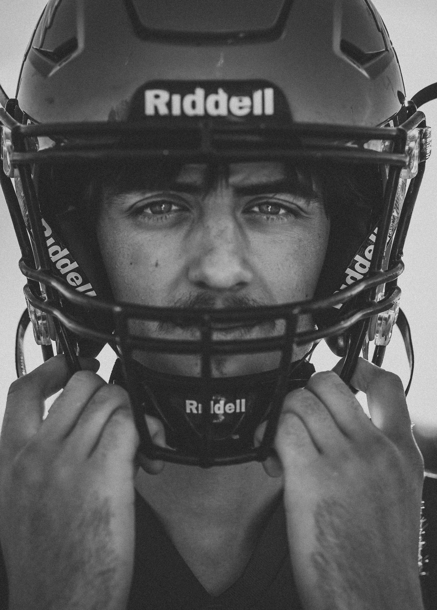 Close-up portrait of athlete wearing black Riddell football helmet.