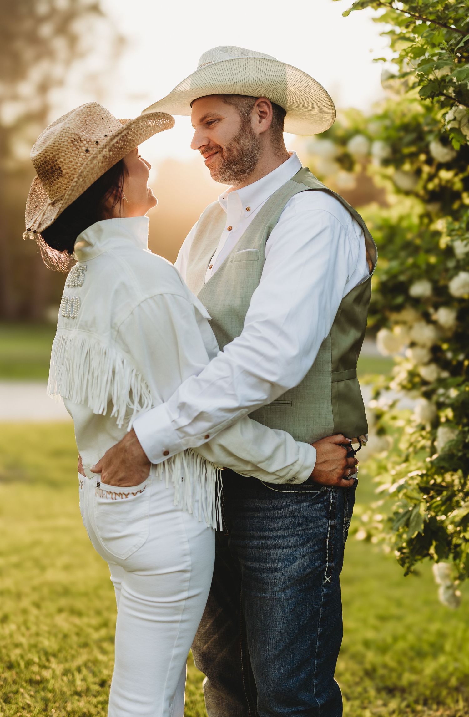 Couple in western attire sharing intimate moments in a sunlit garden setting.