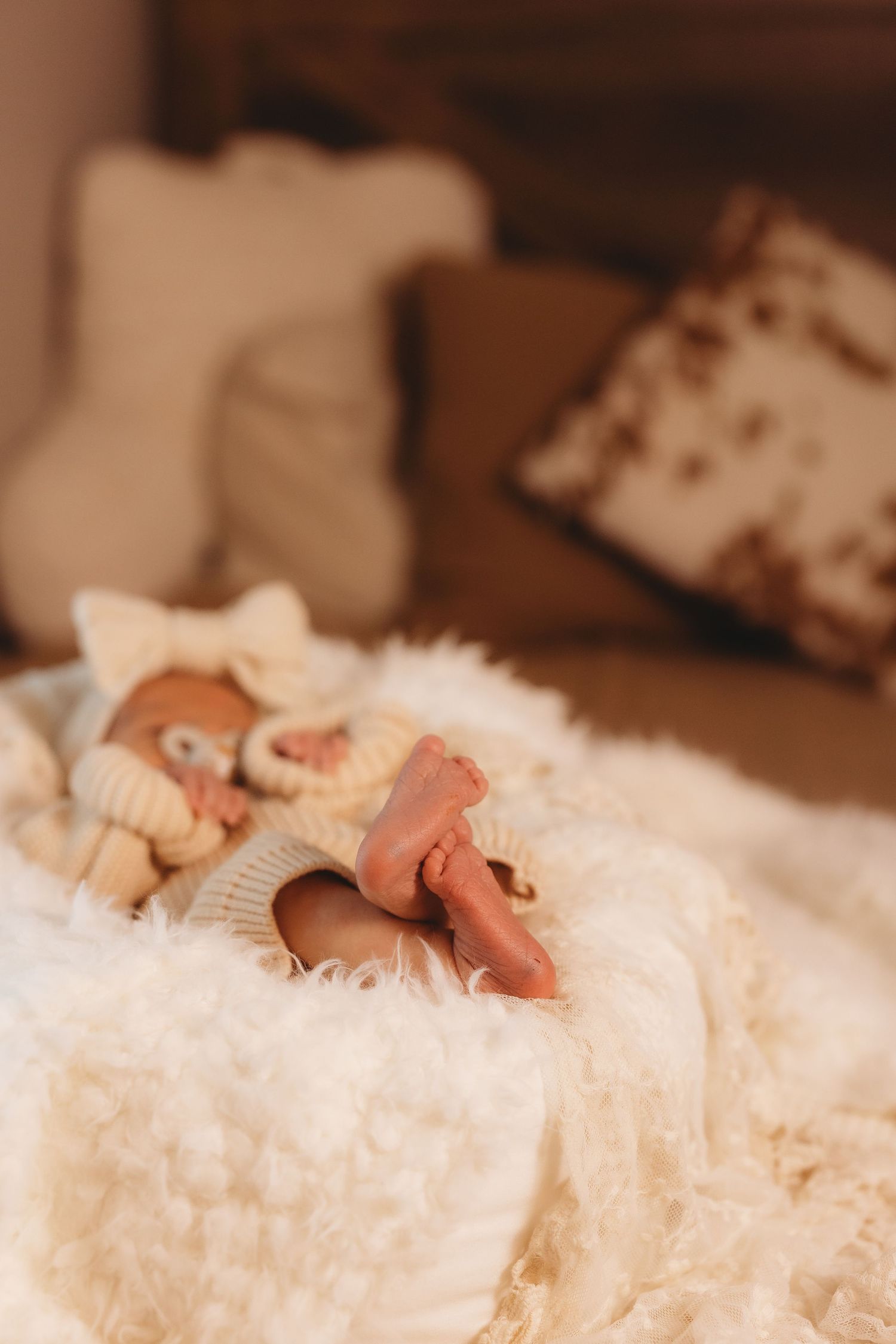 Close-up of tiny baby toes nestled in soft white textured blanket.