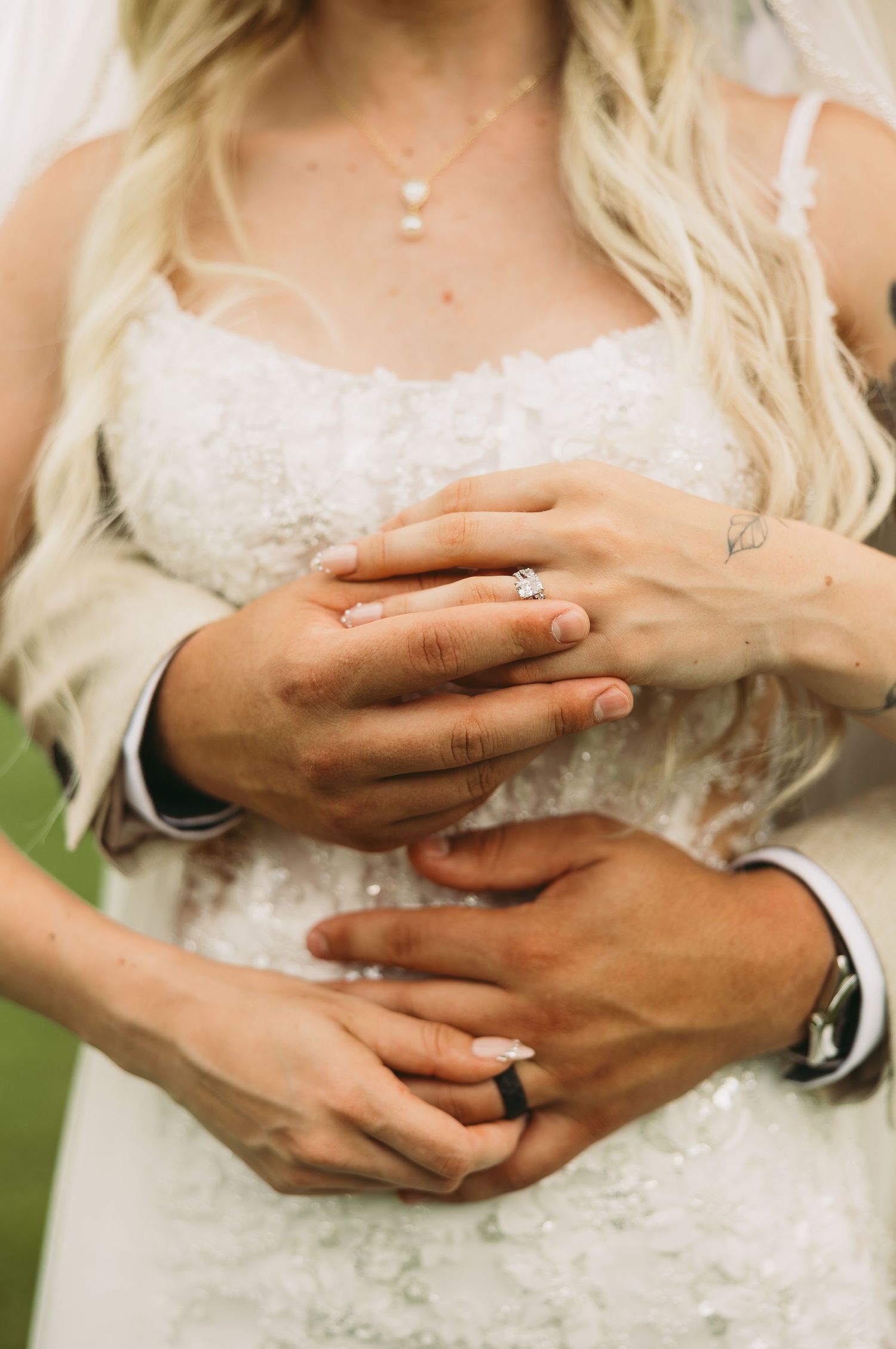 Close-up sequence showing hands with wedding rings embracing in white lace dress.