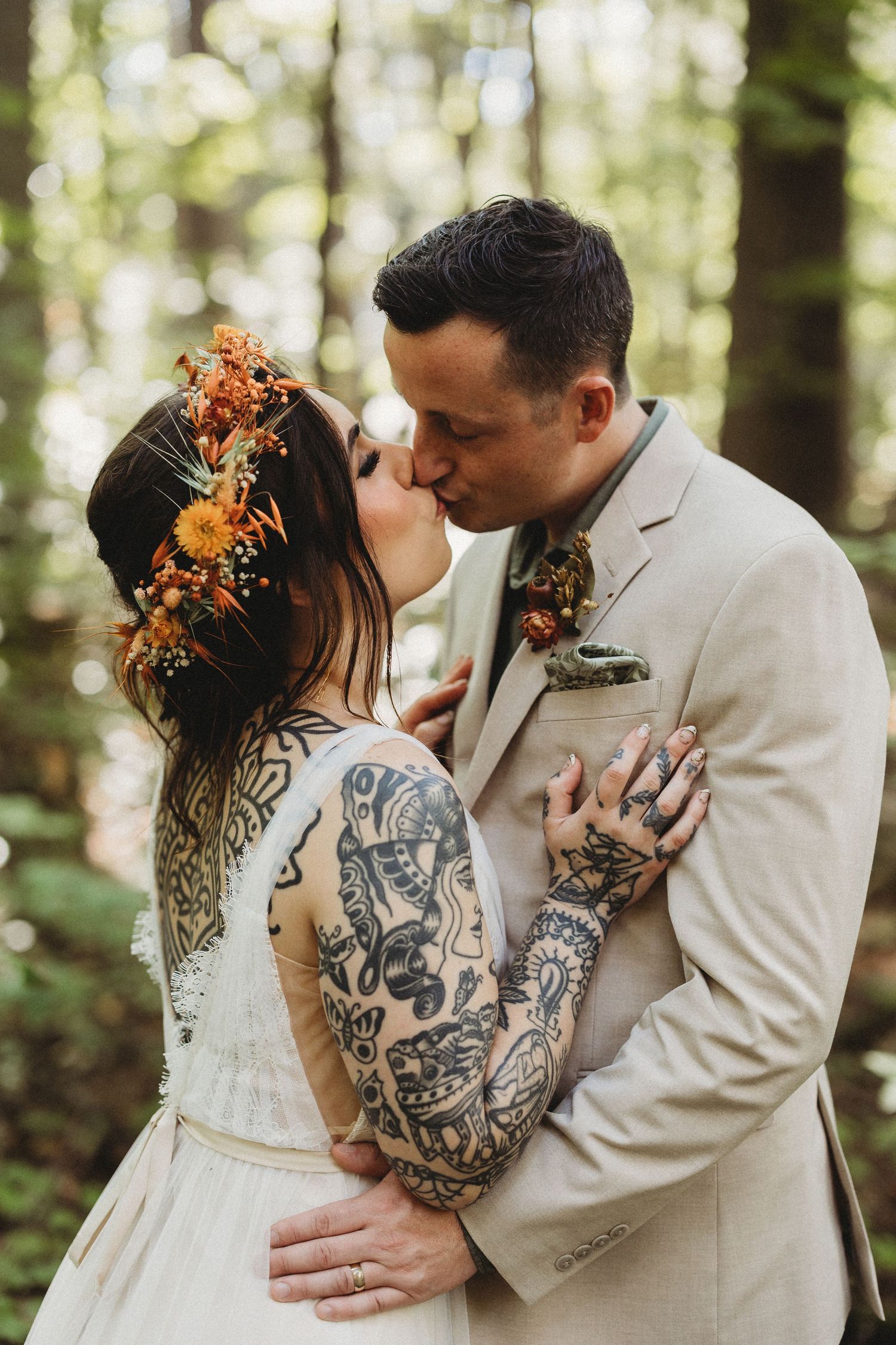 A romantic woodland wedding scene with a couple embracing, featuring a beige suit and floral crown with autumn colors.