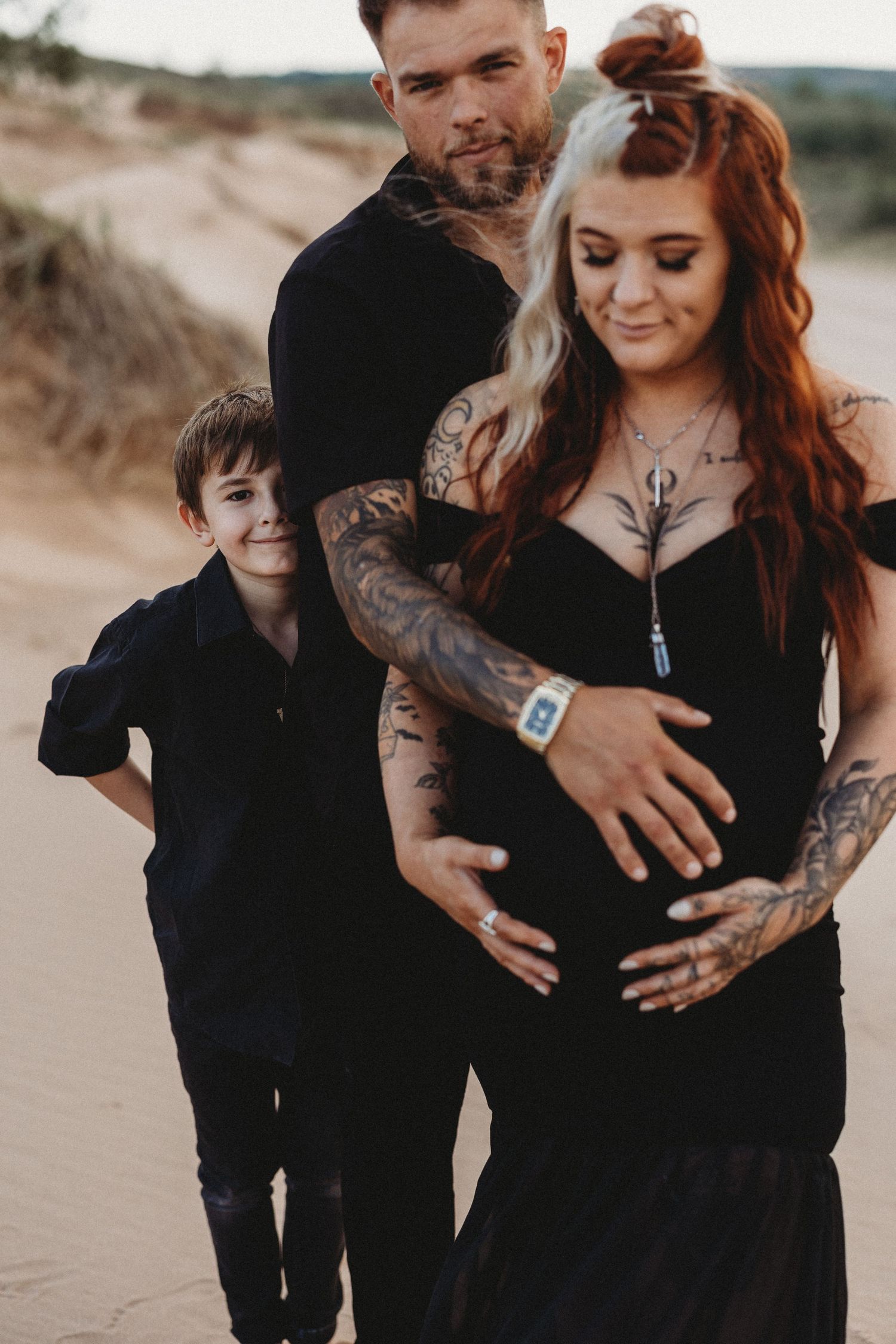Family maternity photo on beach with everyone wearing black.