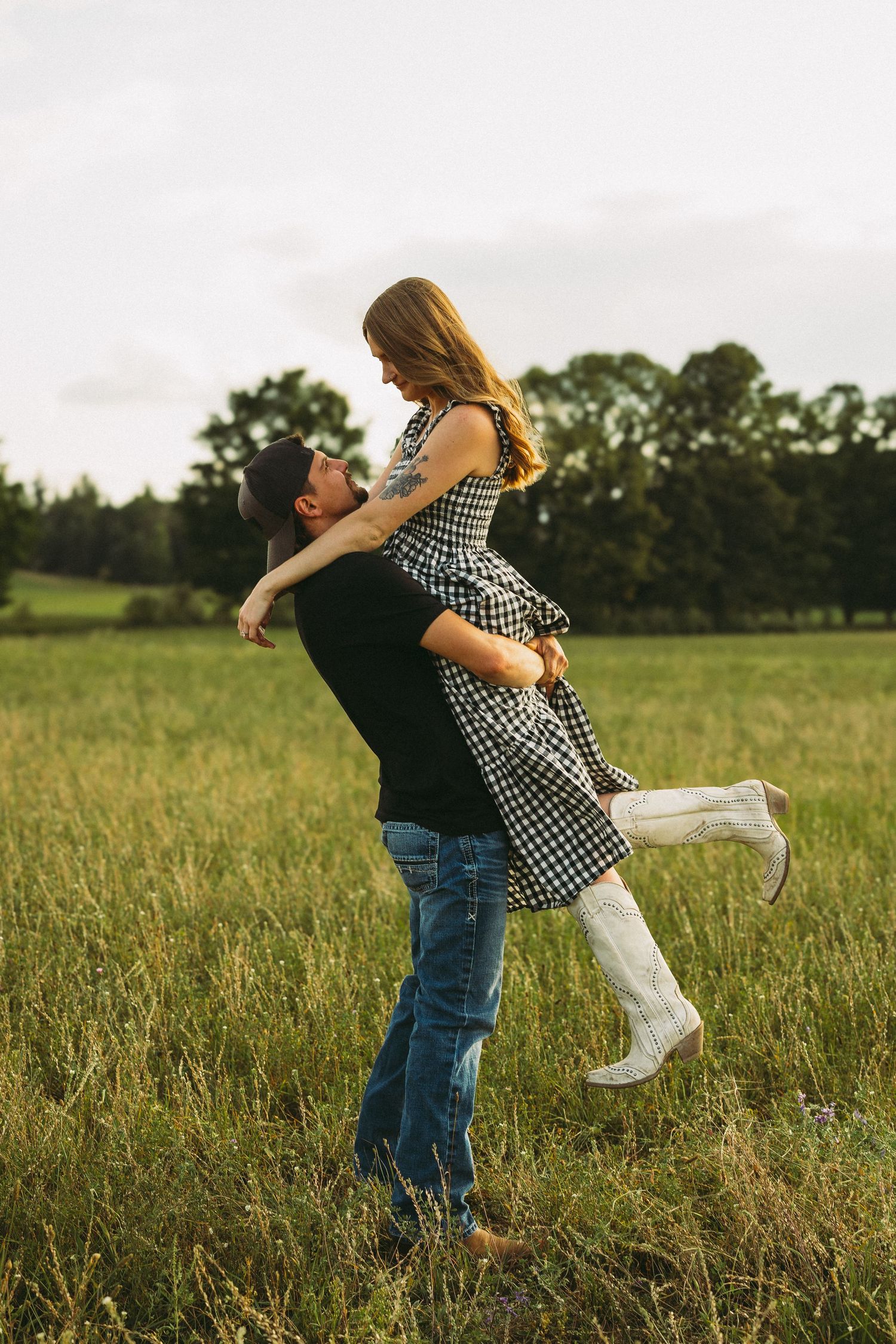 Couple in casual wear spinning and dancing together in a grassy meadow.
