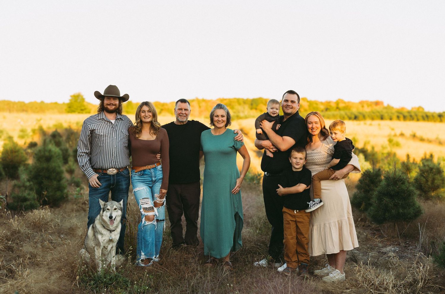 Family group photo with dog in outdoor setting during golden hour.